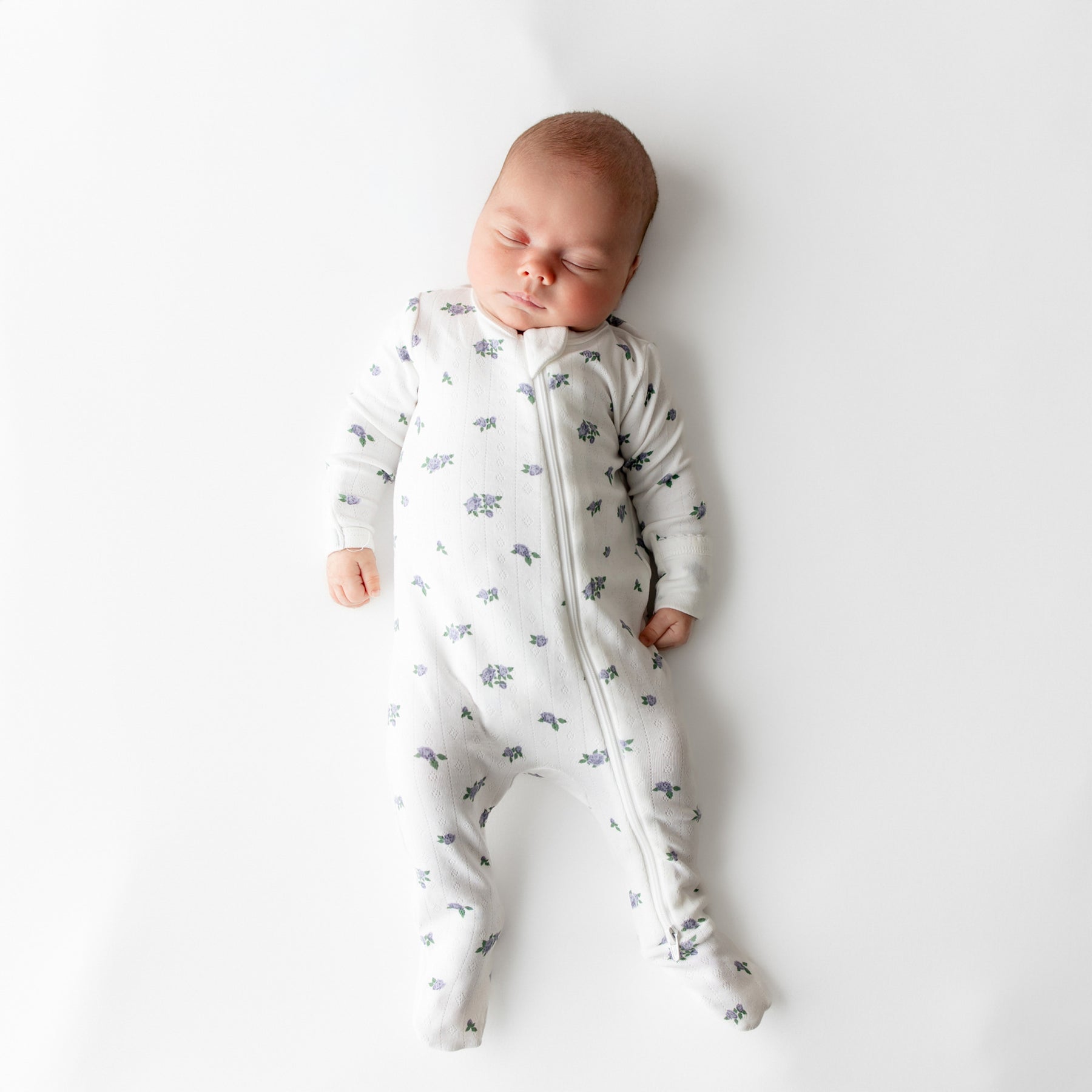 Sleeping newborn wearing the Pointelle Zippered Footie in Spray Rose