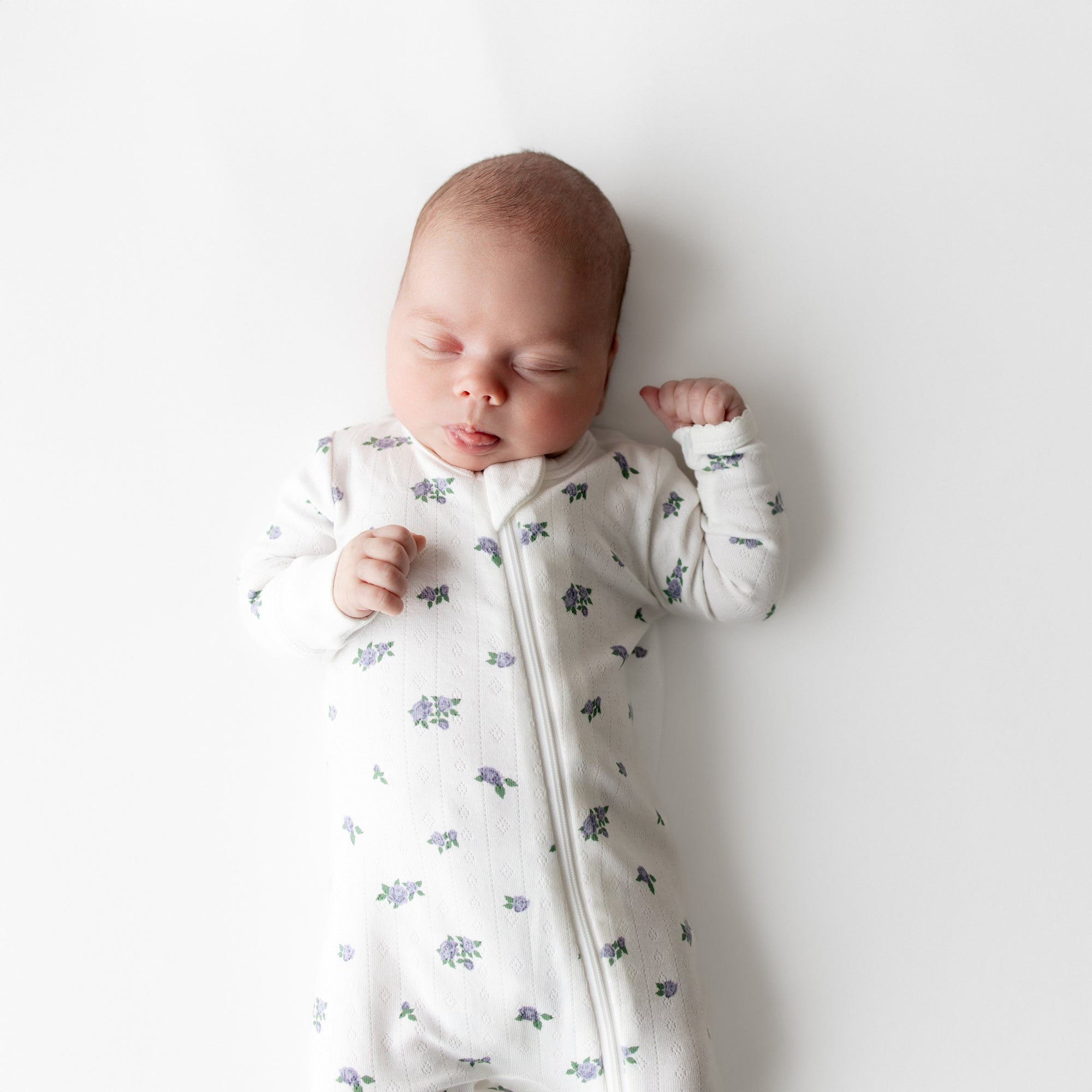 Close up of sleeping newborn wearing the Pointelle Zippered Footie in Spray Rose