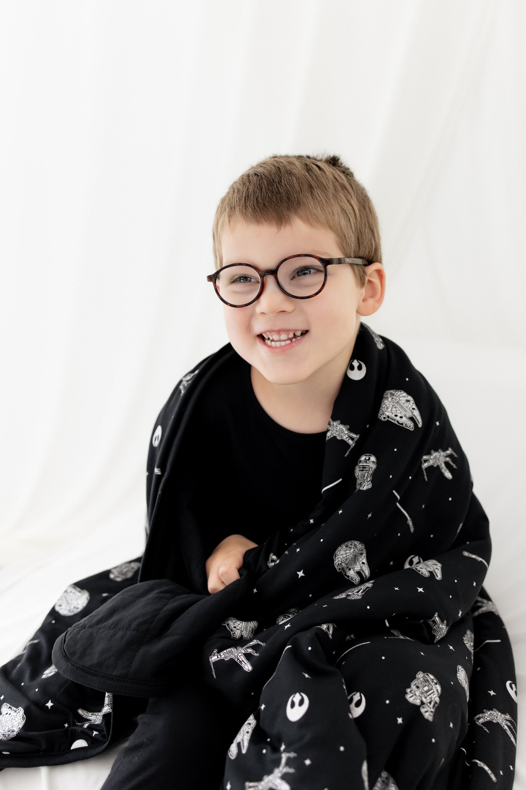 Close up of a young boy with the Toddler Blanket in STAR WARS™ 1.0 wrapped around his shoulders