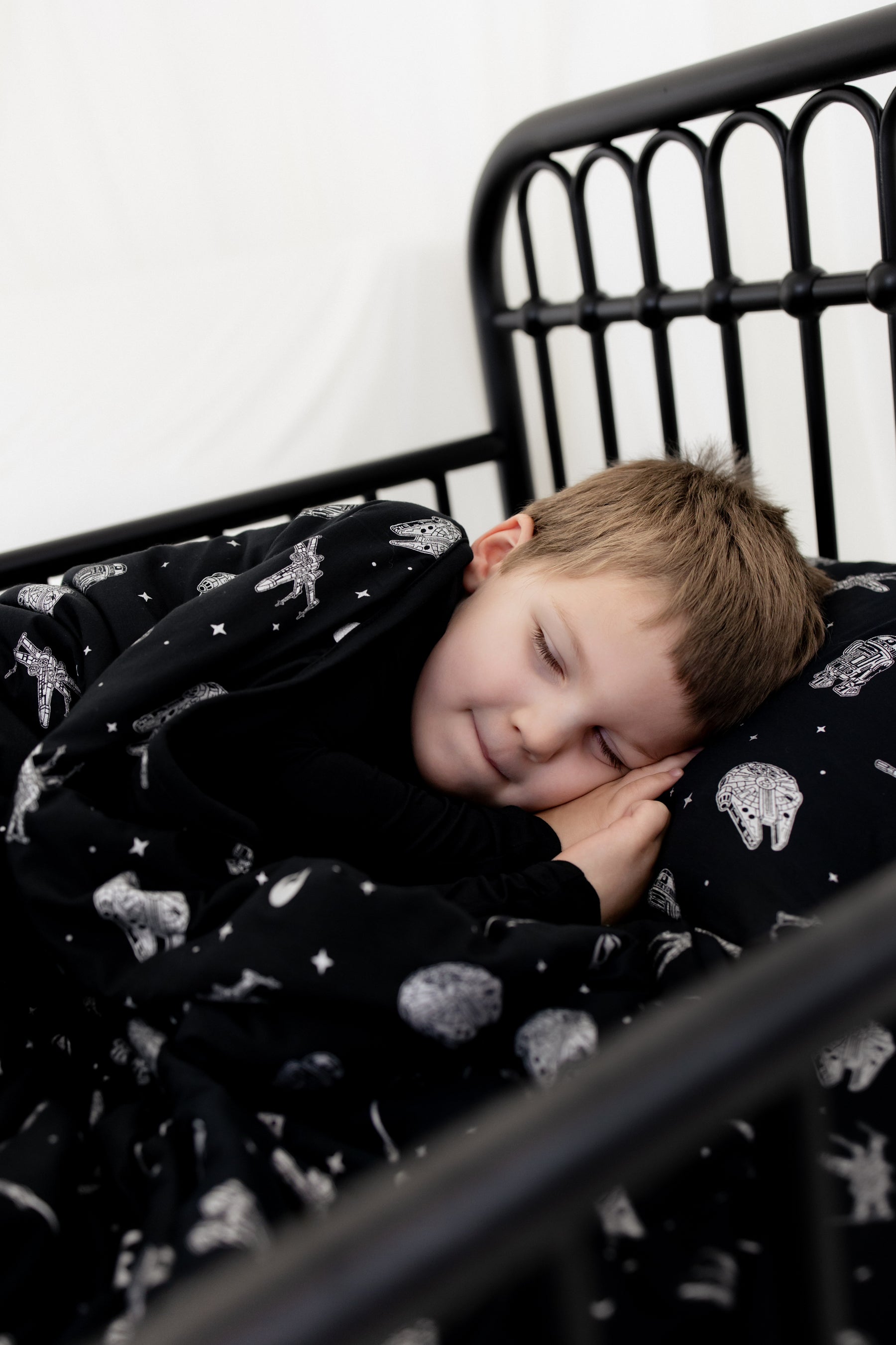 Boy sleeping in a bed laying on a pillow with the Toddler Pillowcase in STAR WARS™ on it 