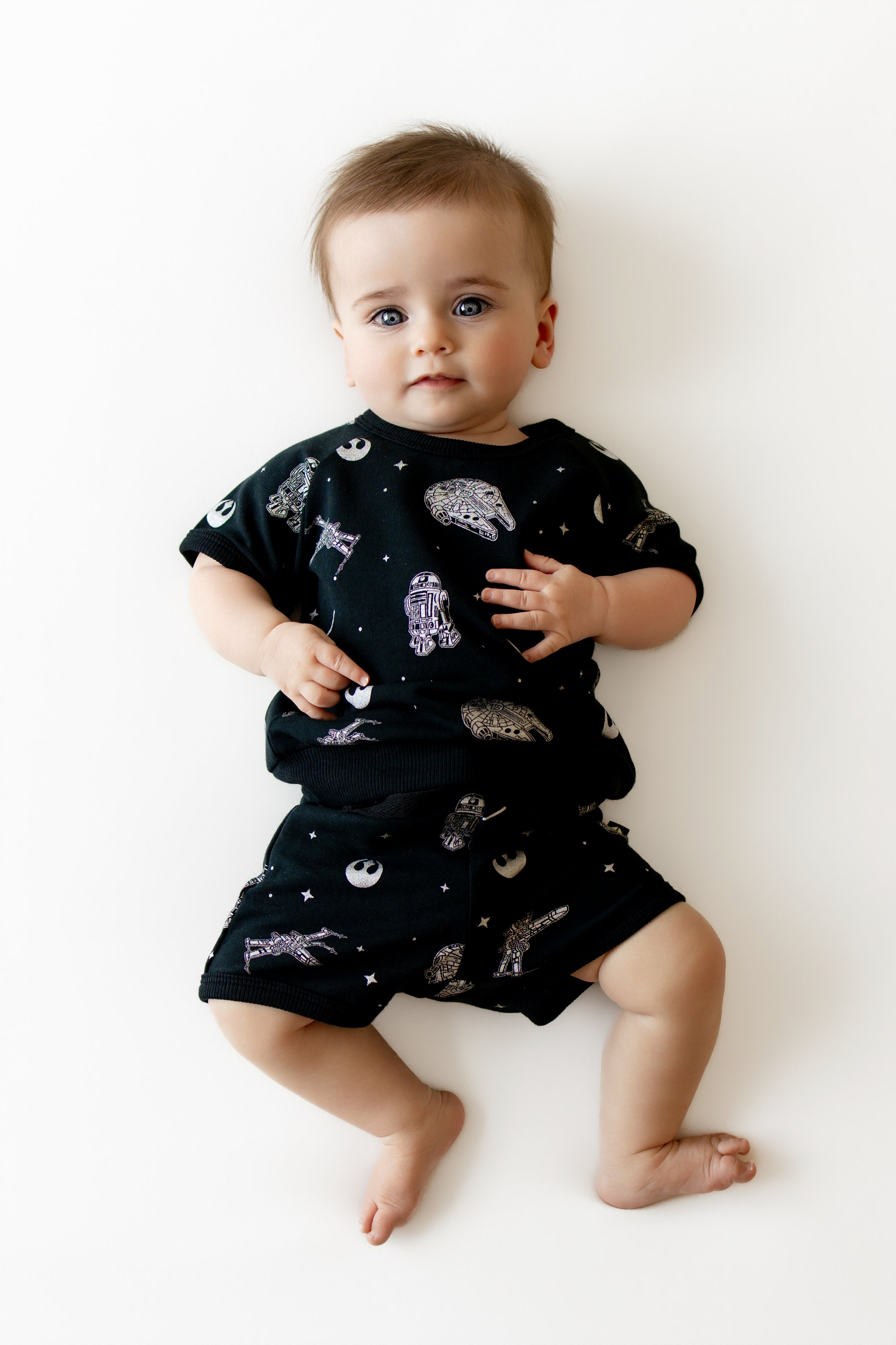 Toddler wearing the Short Sleeve Jogger Set in STAR WARS™ laying on a white surface