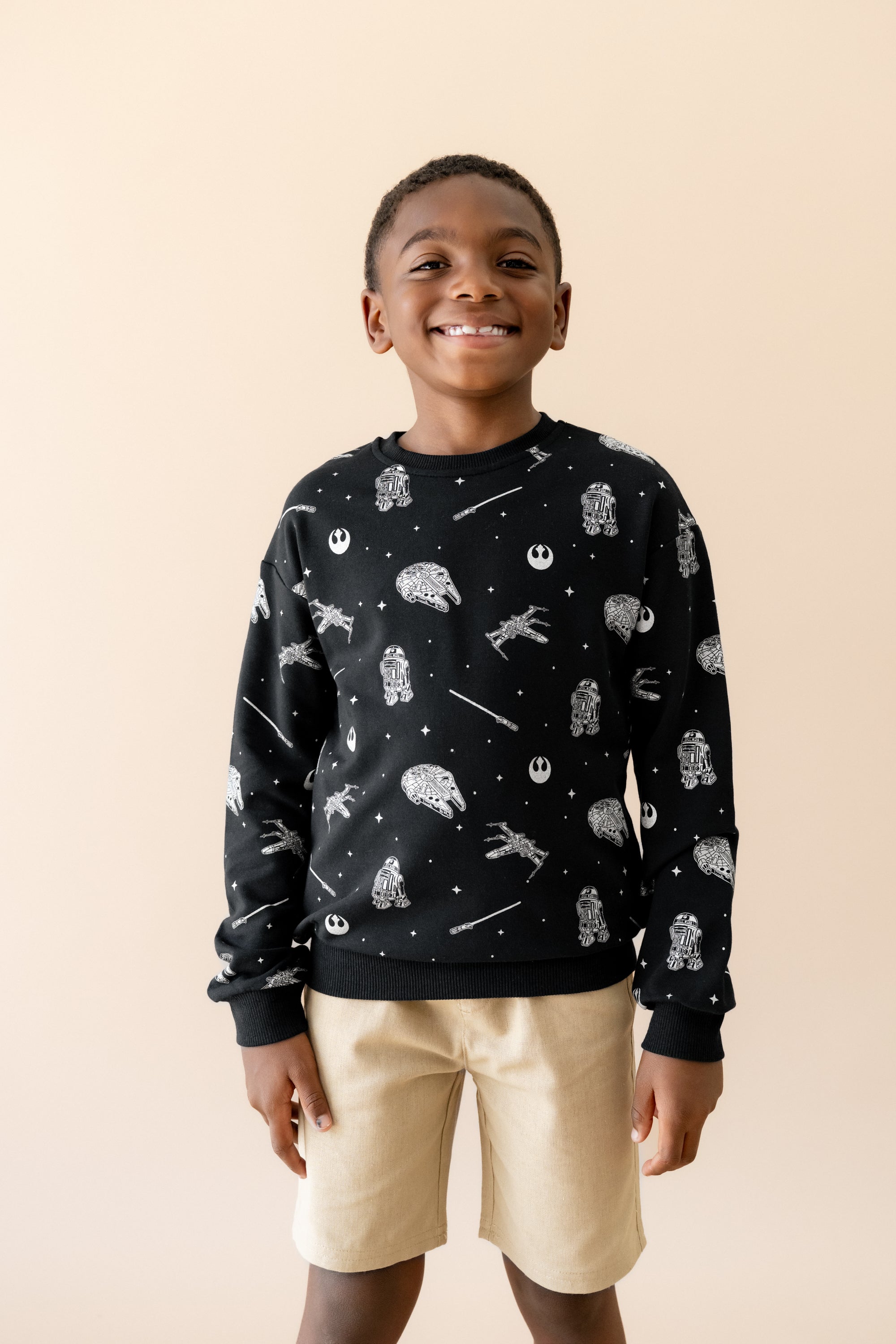 Smiling boy wearing the Sweatshirt in STAR WARS™ paired with tan shorts