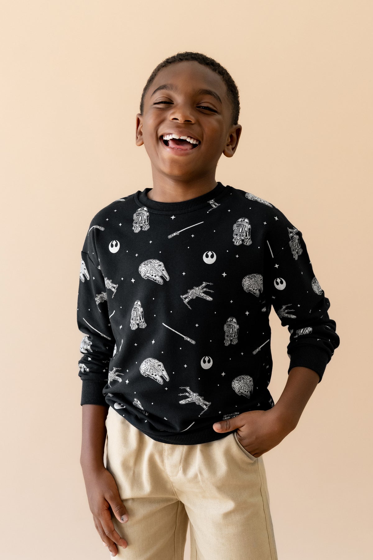 Smiling boy wearing the Sweatshirt in STAR WARS™ with tan shorts