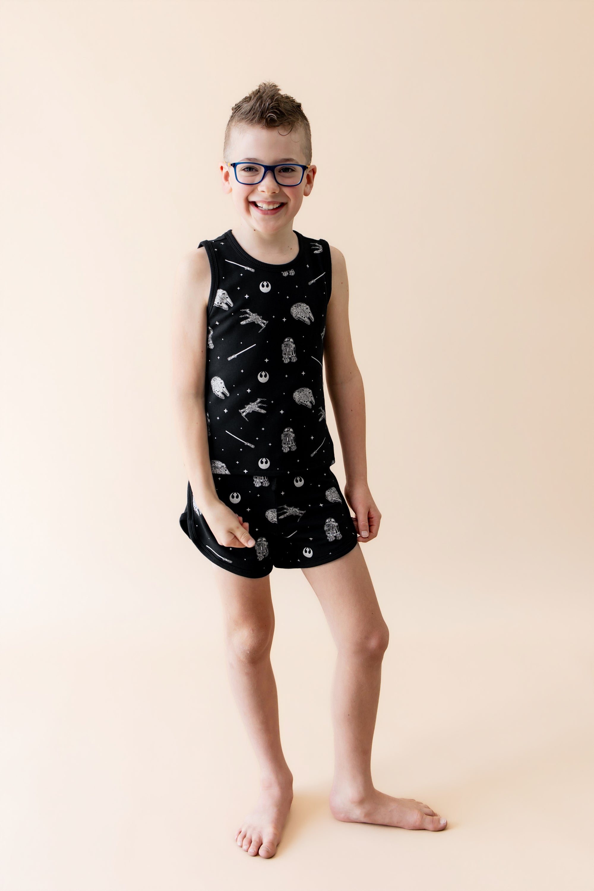 Smiling boy wearing the Tank Jogger Set in STAR WARS™ in front of a light neutral surface