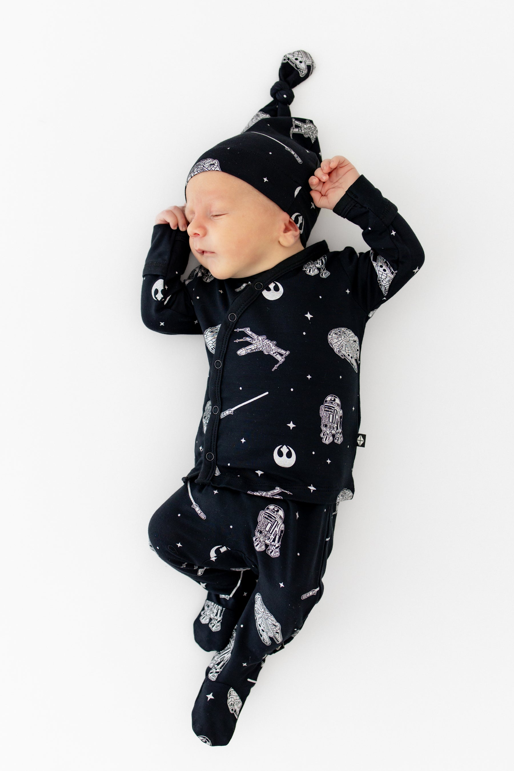 Sleeping infant stretching wearing the Take Me Home Set with Cap in STAR WARS™ laying on a white surface
