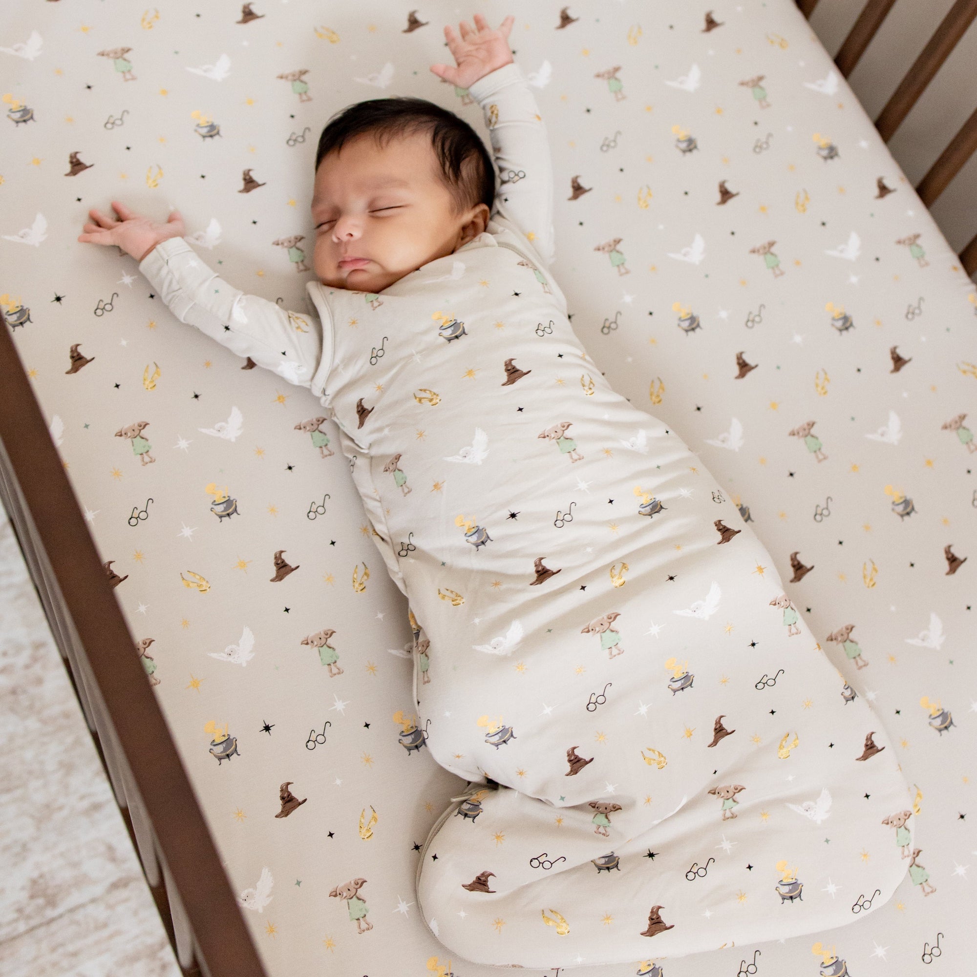 Baby asleep in a harry potter patterned sleep sack in a crib