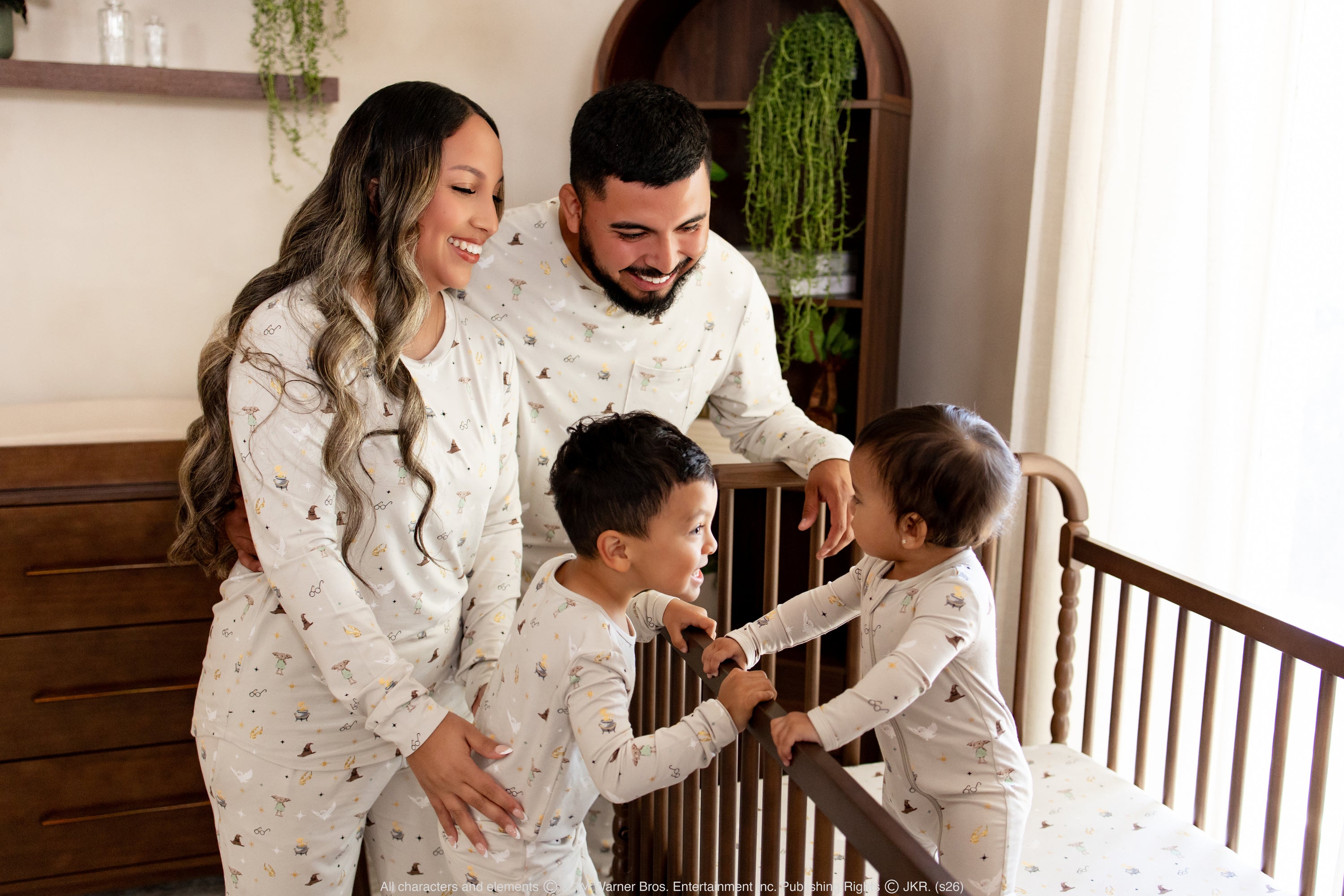 Family of 4 wearing matching bamboo harry potter inspired family pajamas in a nursery setting 