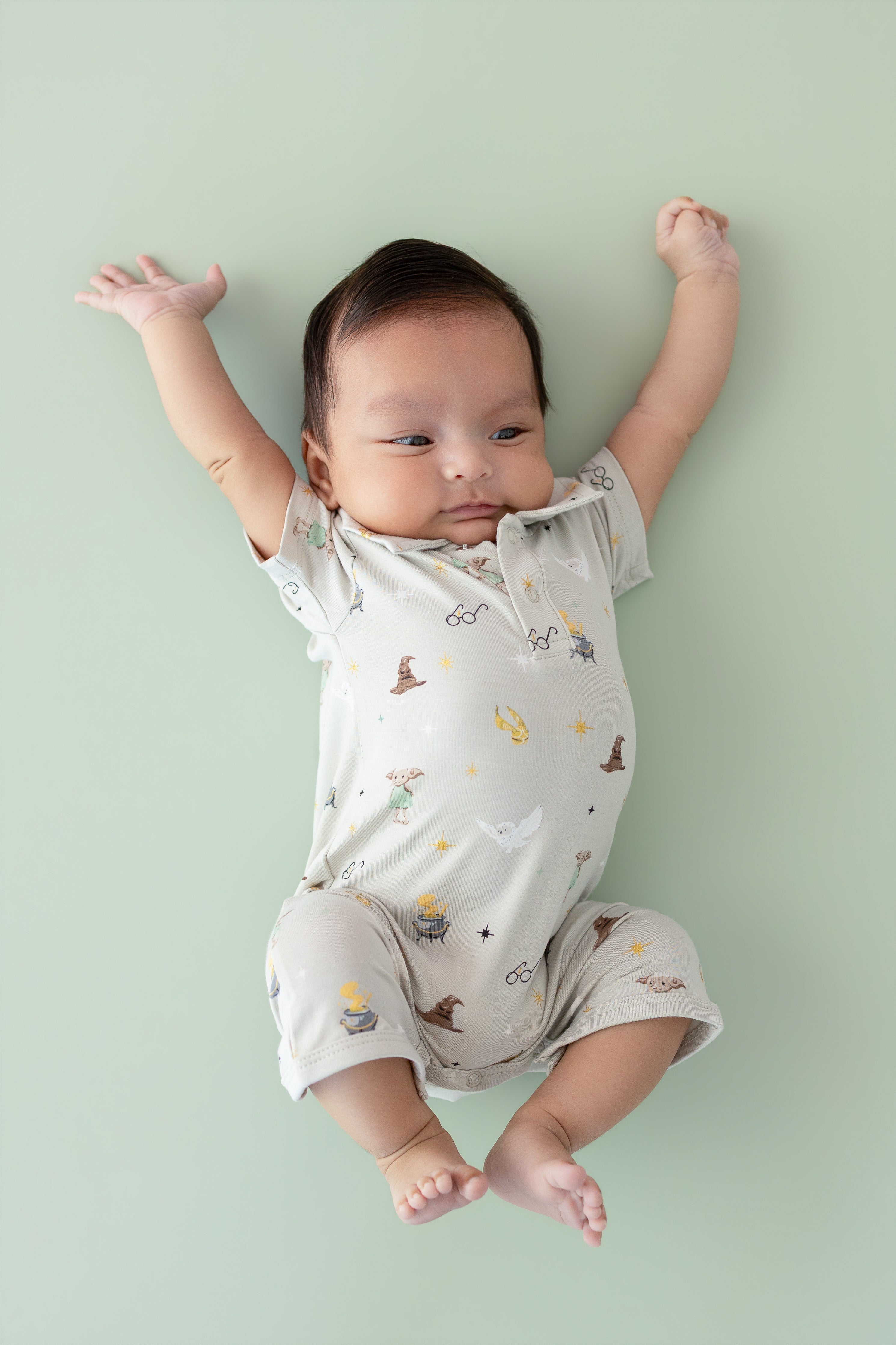 Baby wearing a polo shortall with Harry Potter prints on a cream fabric