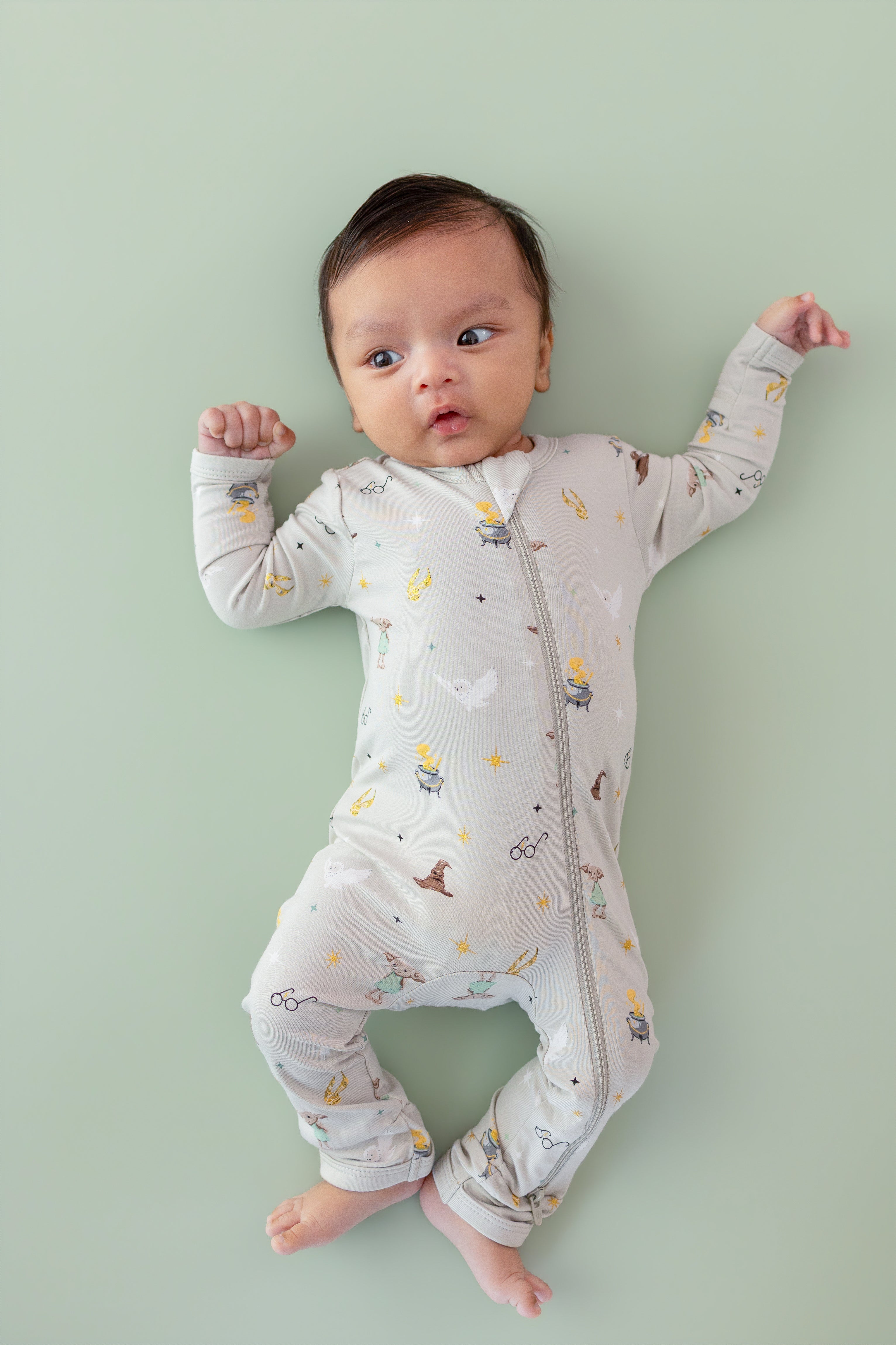 Baby wearing a Harry Potter patterned Zippered Romper on a green background