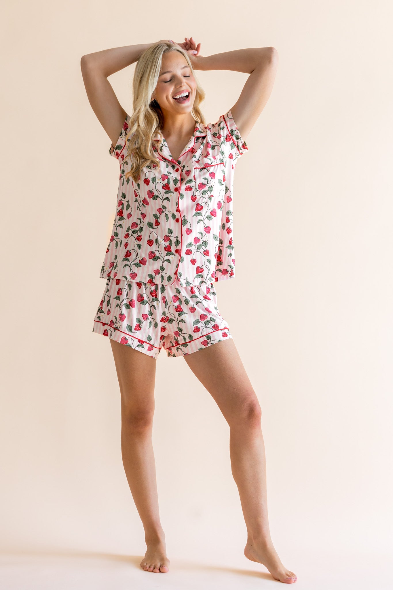 Woman wearing a strawberry floral pajama set against a beige background