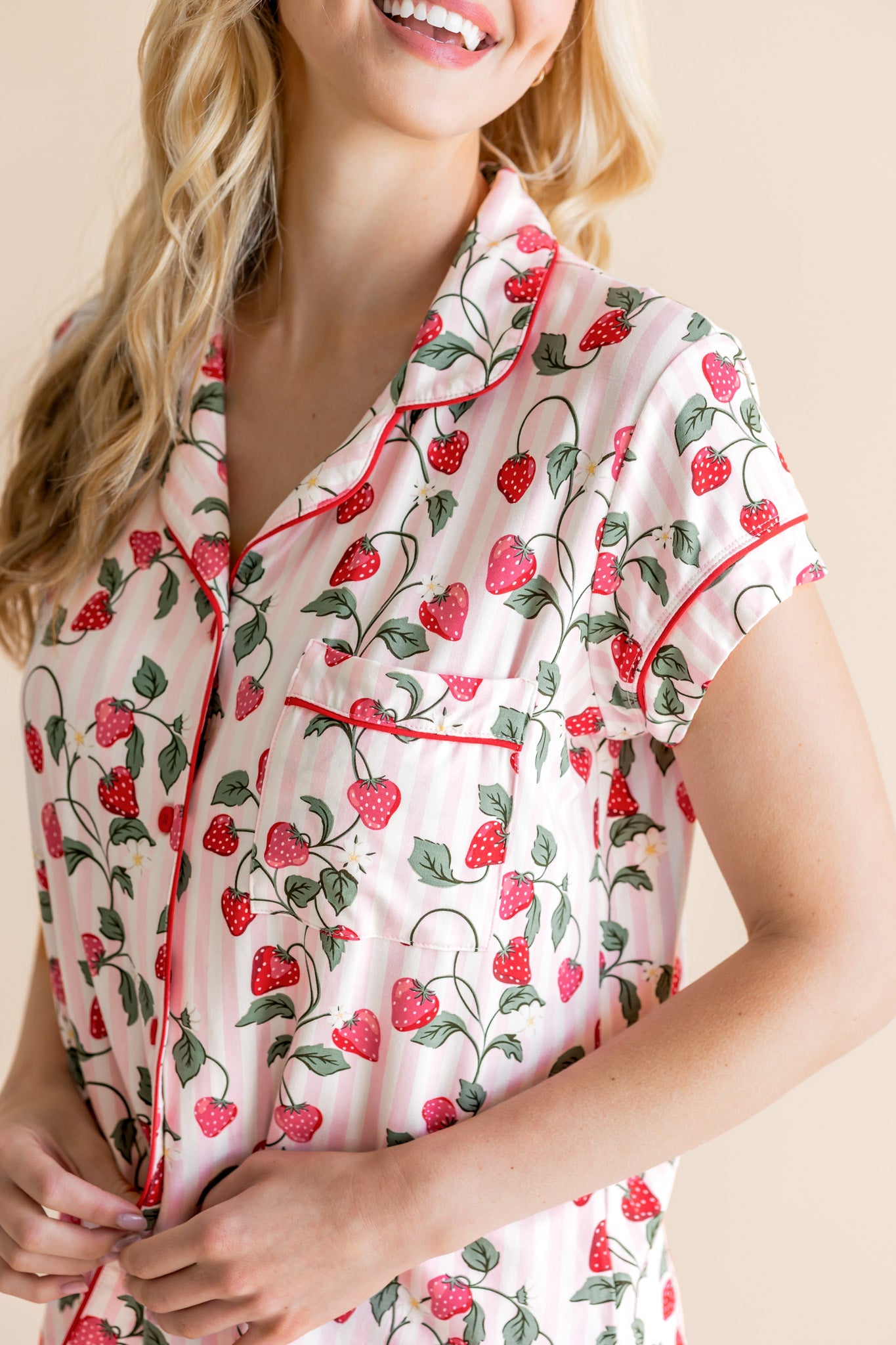 Woman wearing a strawberry patterned pajama top with a beige background