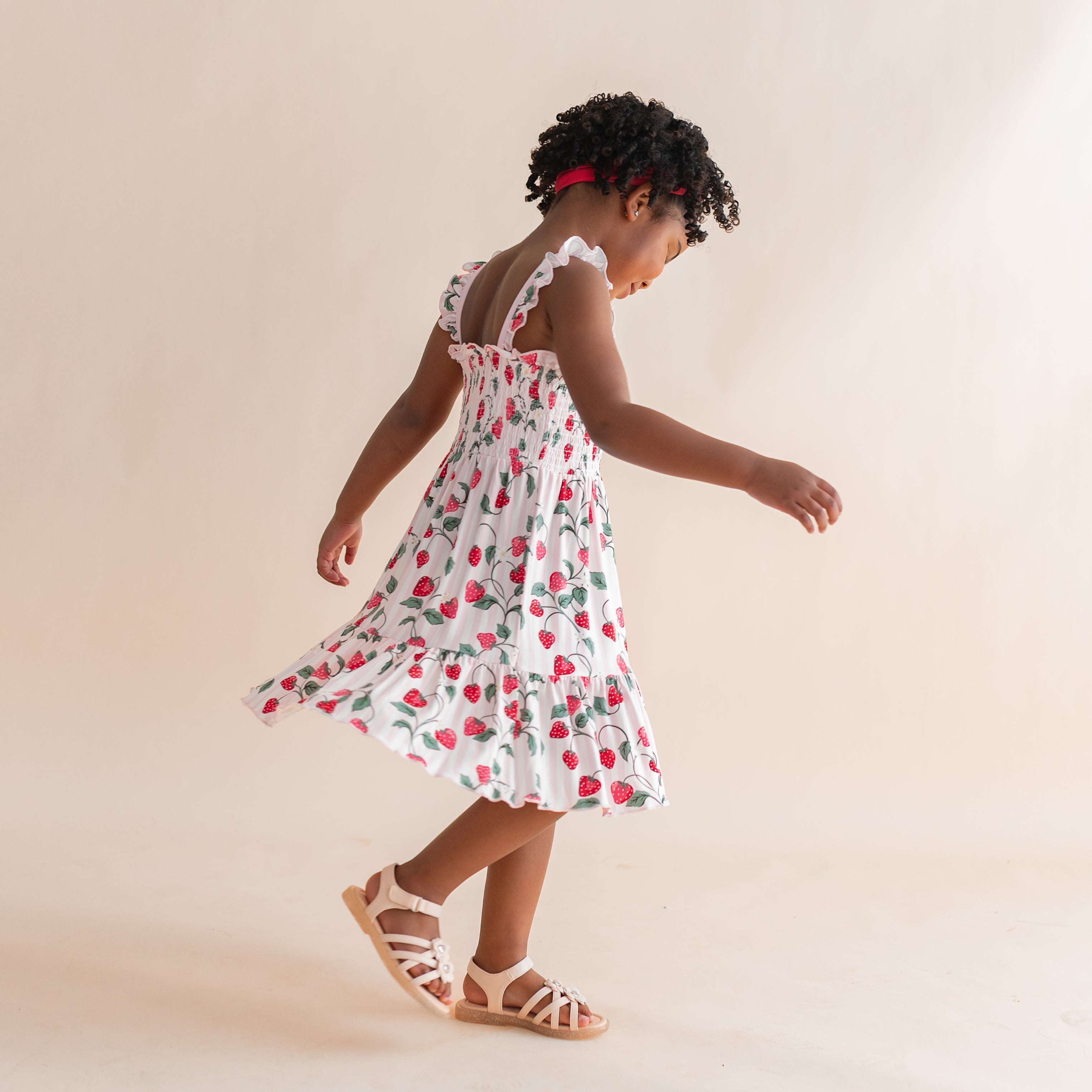 Young girl twirling in the Smocked Dress in Strawberry Fields