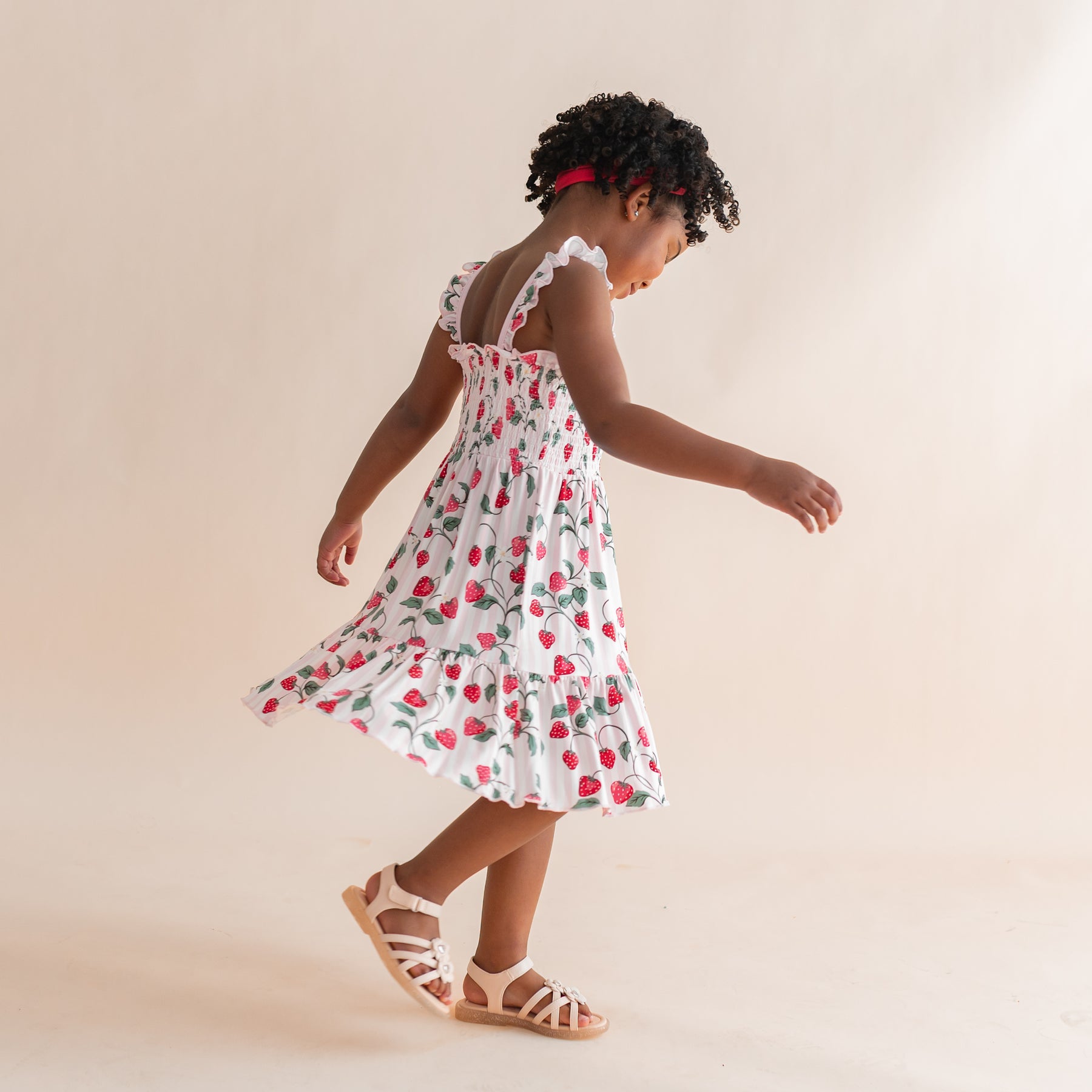 Young girl twirling in the Smocked Dress in Strawberry Fields