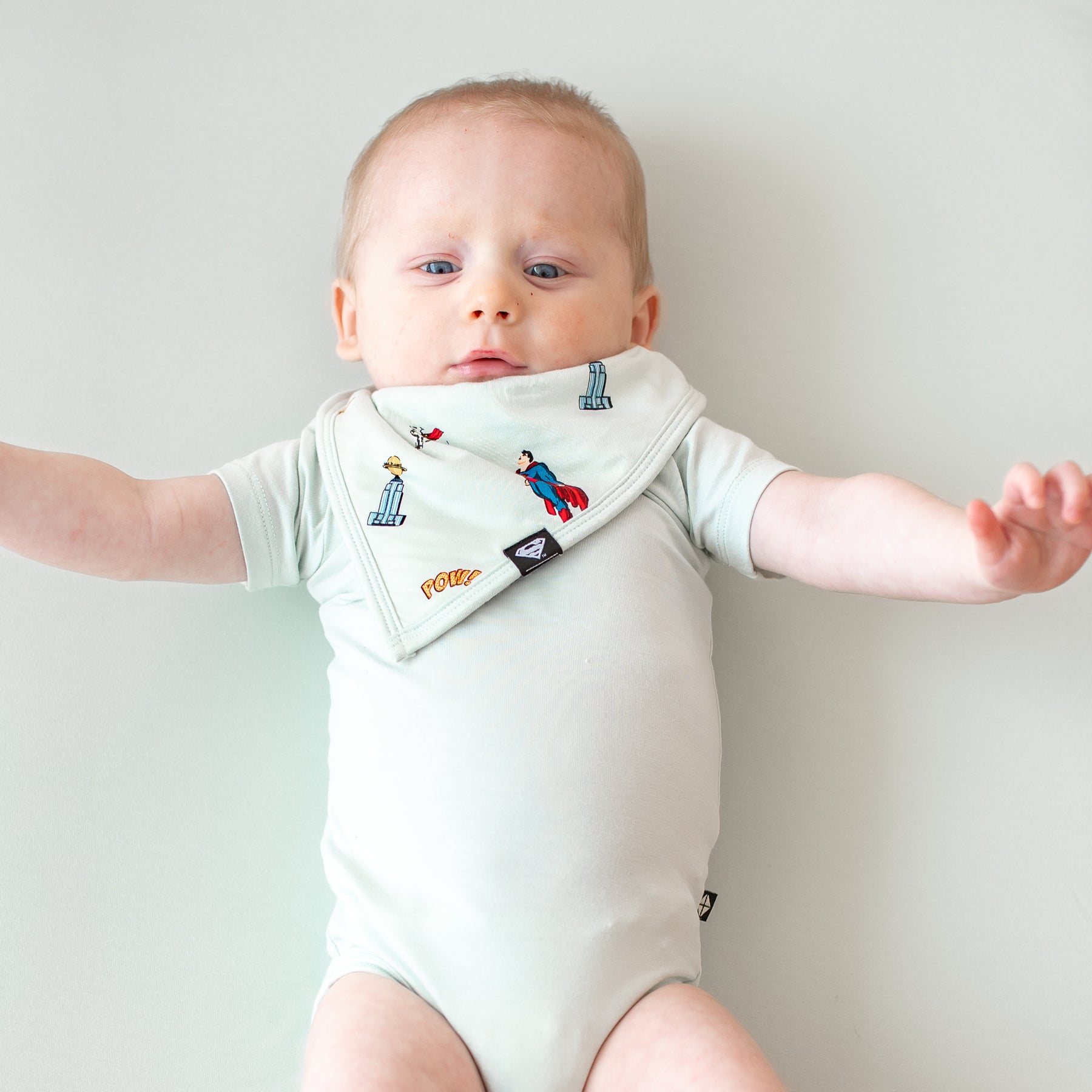 Infant wearing the Bib in Superman™ paired with a Dew Short Sleeve Bodysuit
