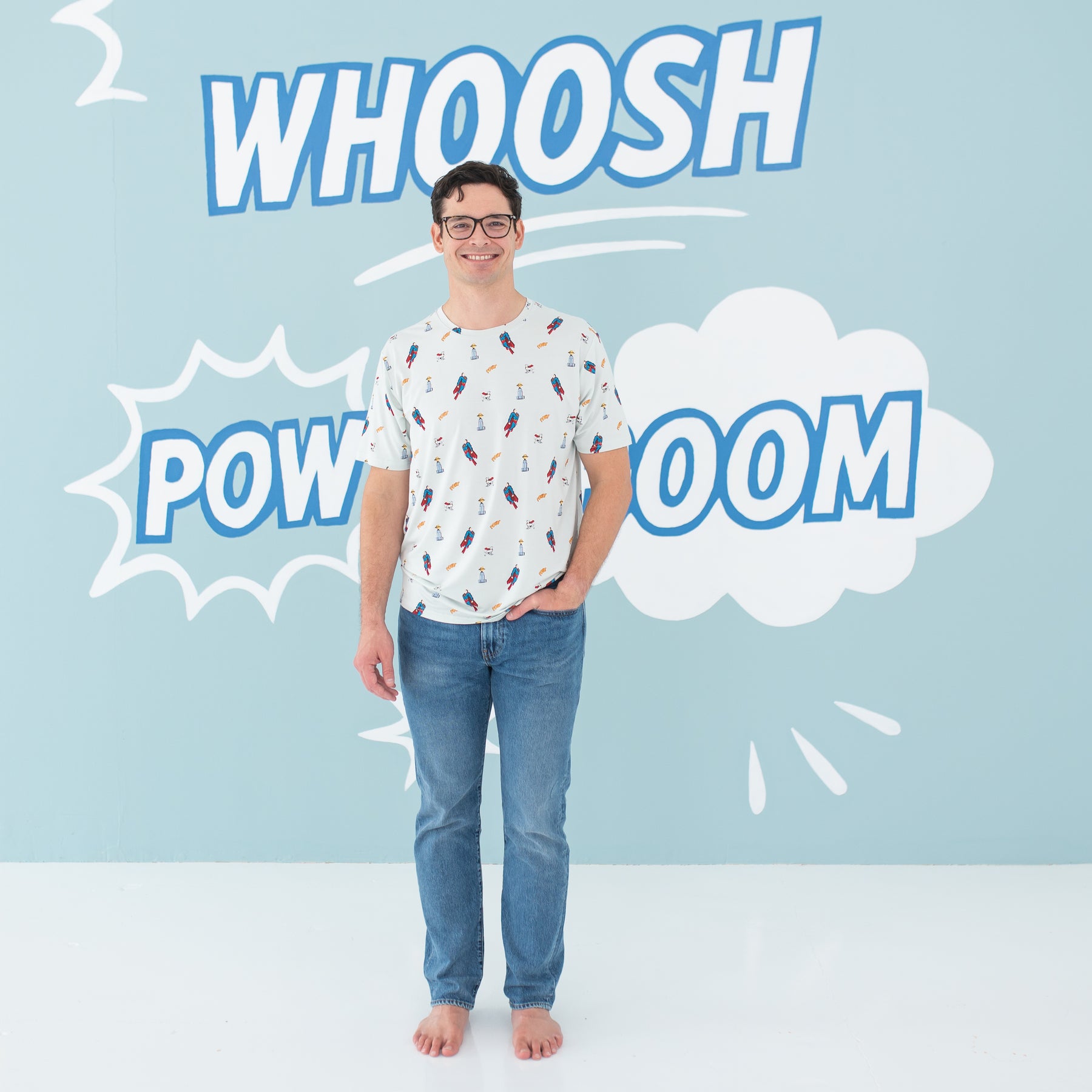 Smiling male model standing wearing the Men's Crew Neck Tee in Superman™ paired with medium wash jeans