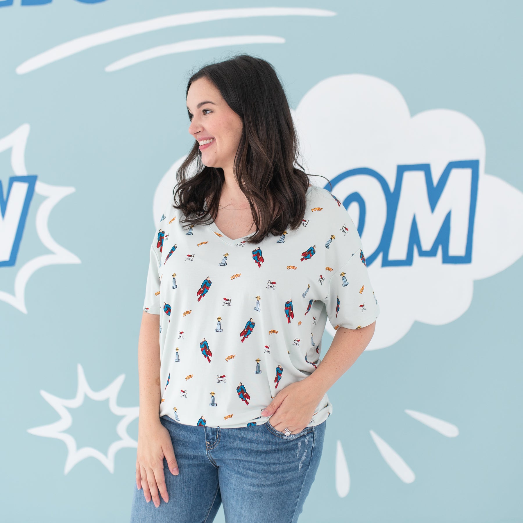 Smiling female model looking off to the side wearing the Women's Relaxed Fit V-Neck in Superman™ with one hand in her jean pocket
