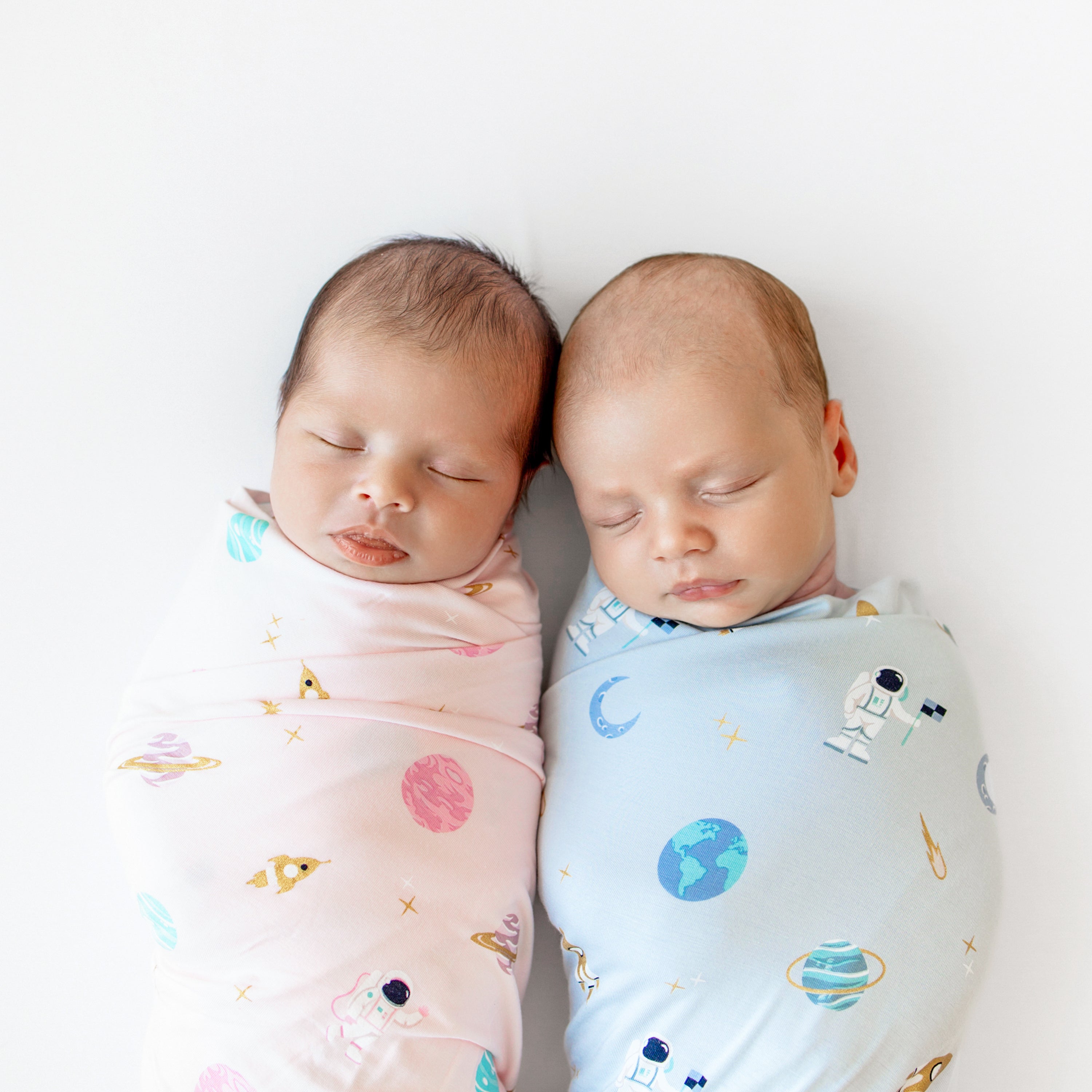 two babies swaddled in ice and sakura space swaddle blanket 