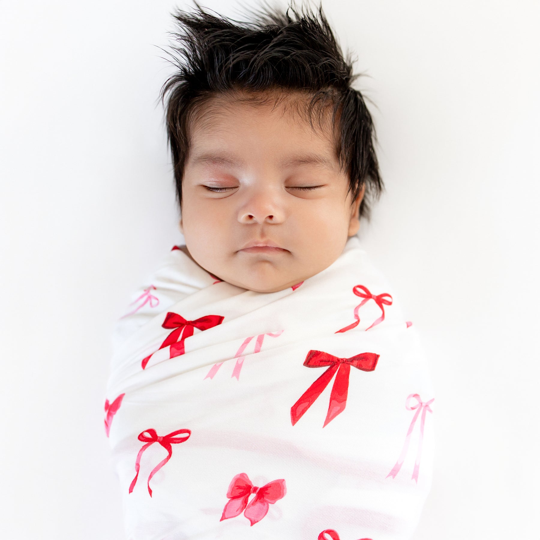 Close up of sleeping newborn swaddled in the Swaddle Blanket in Small Love Bow
