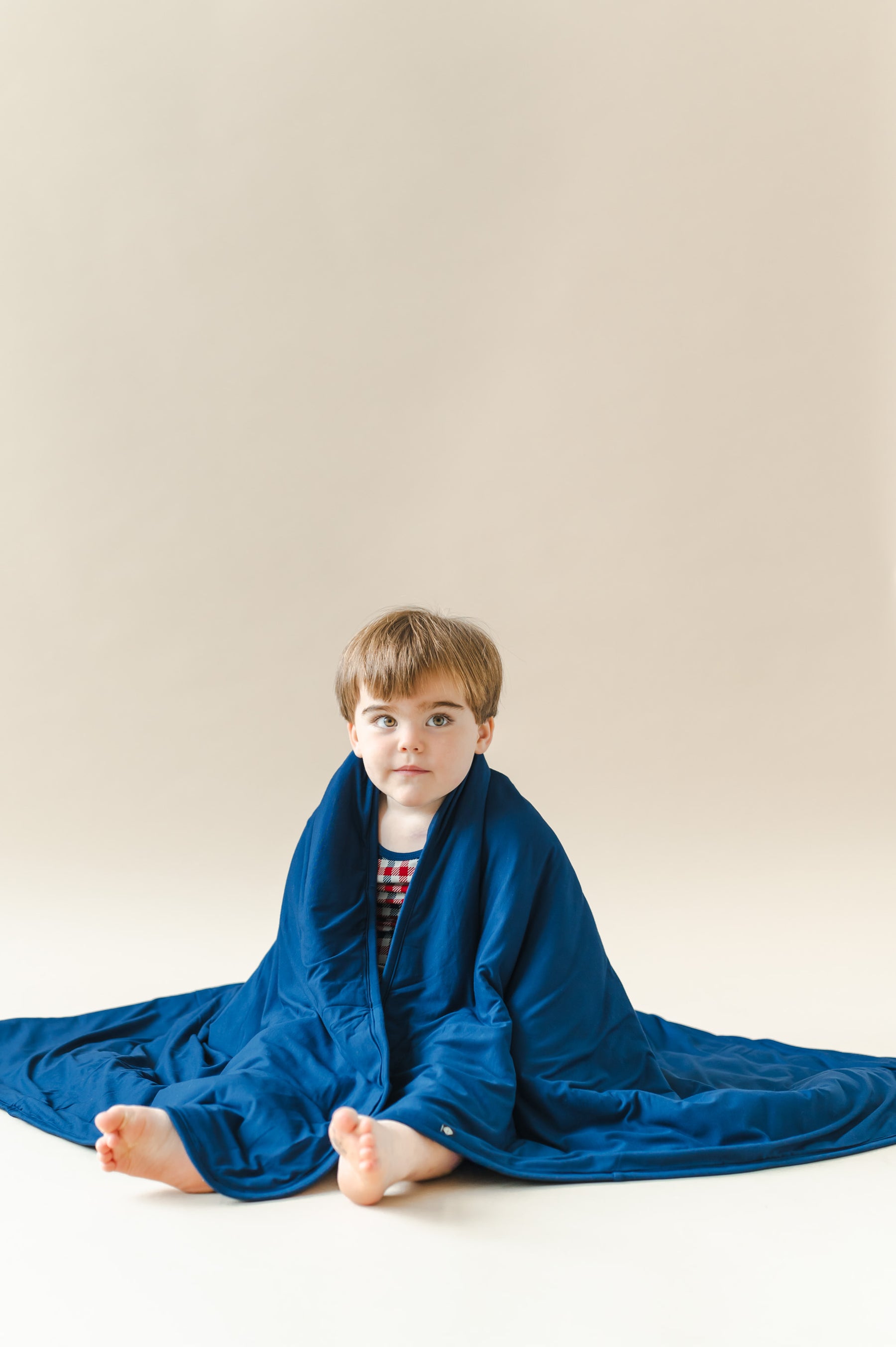 Child wrapped in Toddler Blanket in Tahoe on a beige background