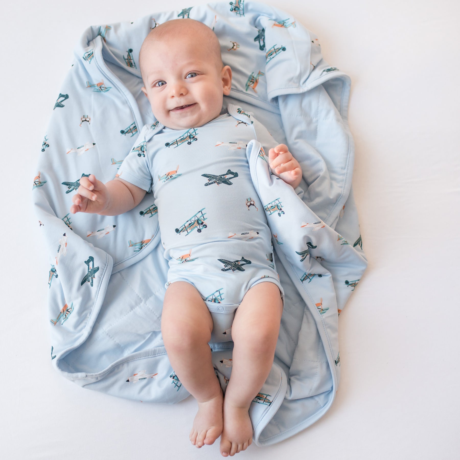 Young infant laying on a Baby Blanket in Take Off wearing a matching short sleeve bodysuit