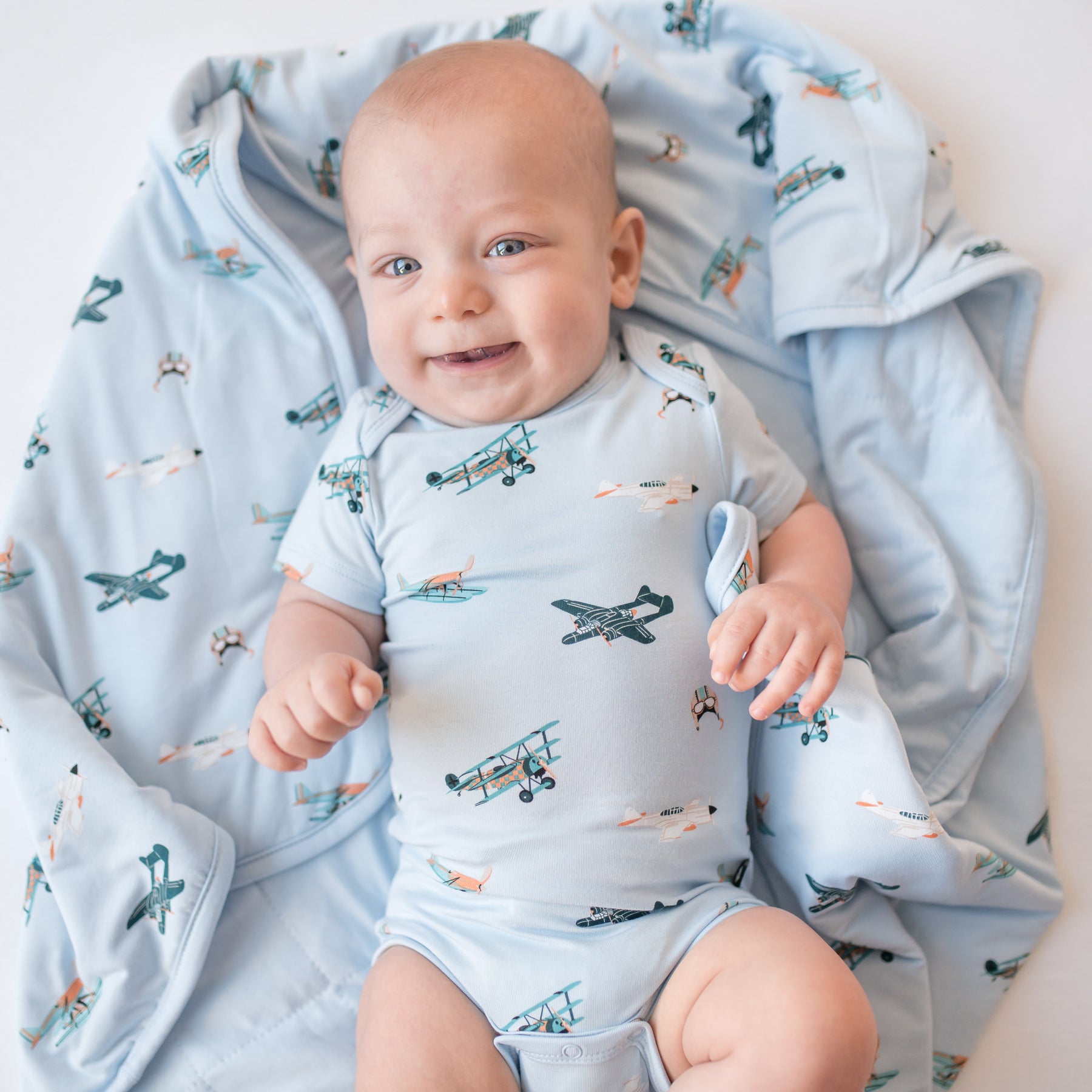 Close up of infant laying on a Baby Blanket in Take Off wearing a matching short sleeve bodysuit