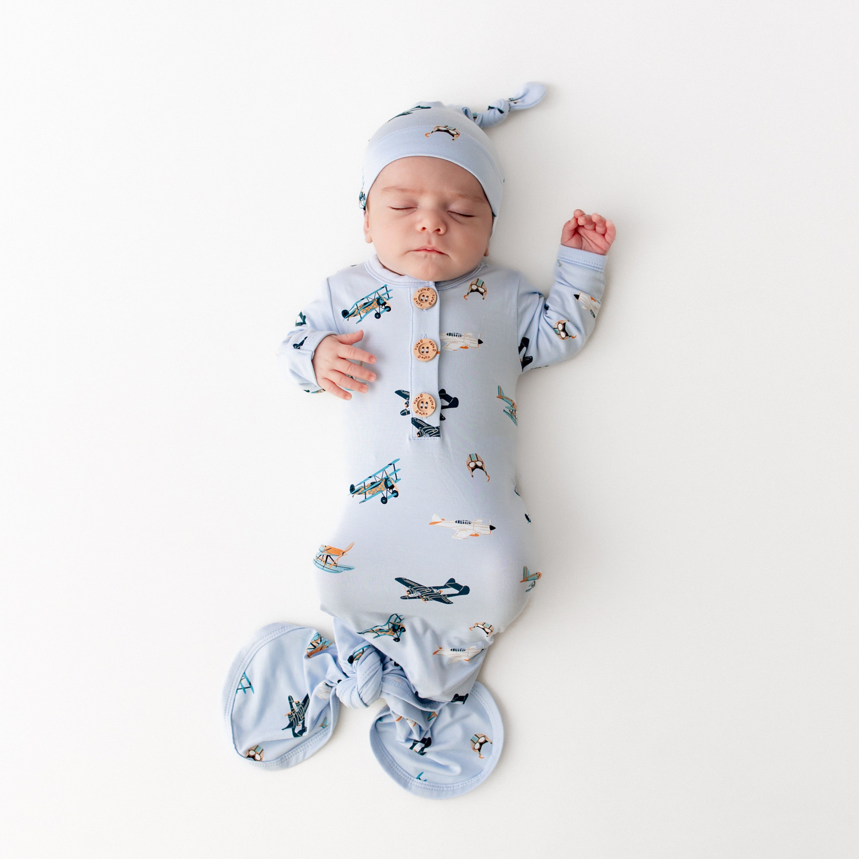 Sleeping newborn wearing the Knotted Gown with Hat Set in Take Off