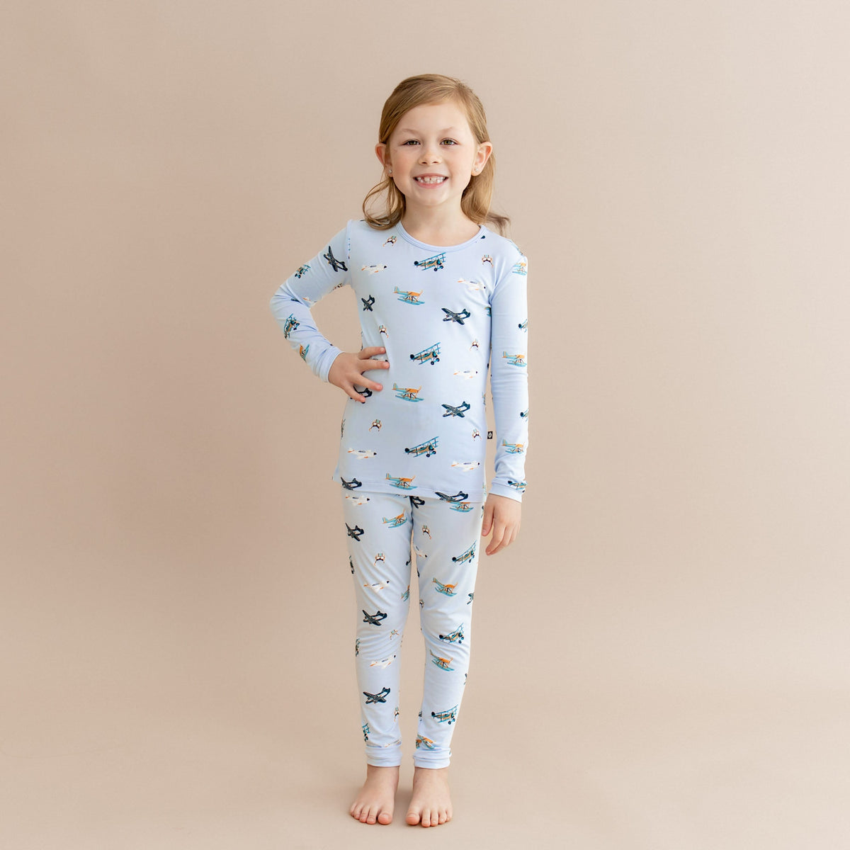 Young girl standing with one hand on her hip wearing the Long Sleeve Pajamas in Take Off