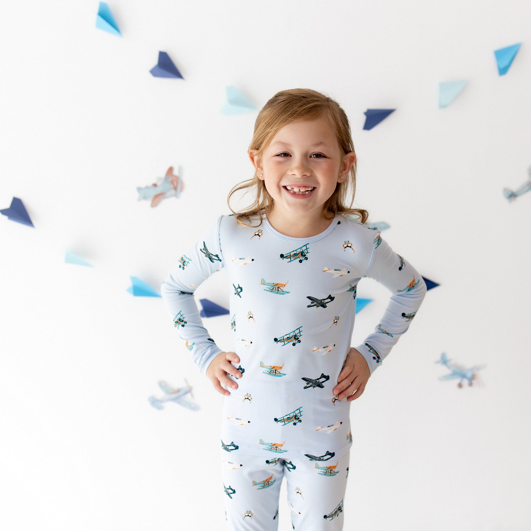 Smiling girl standing with both hands on her hips wearing the Long Sleeve Pajamas in Take Off
