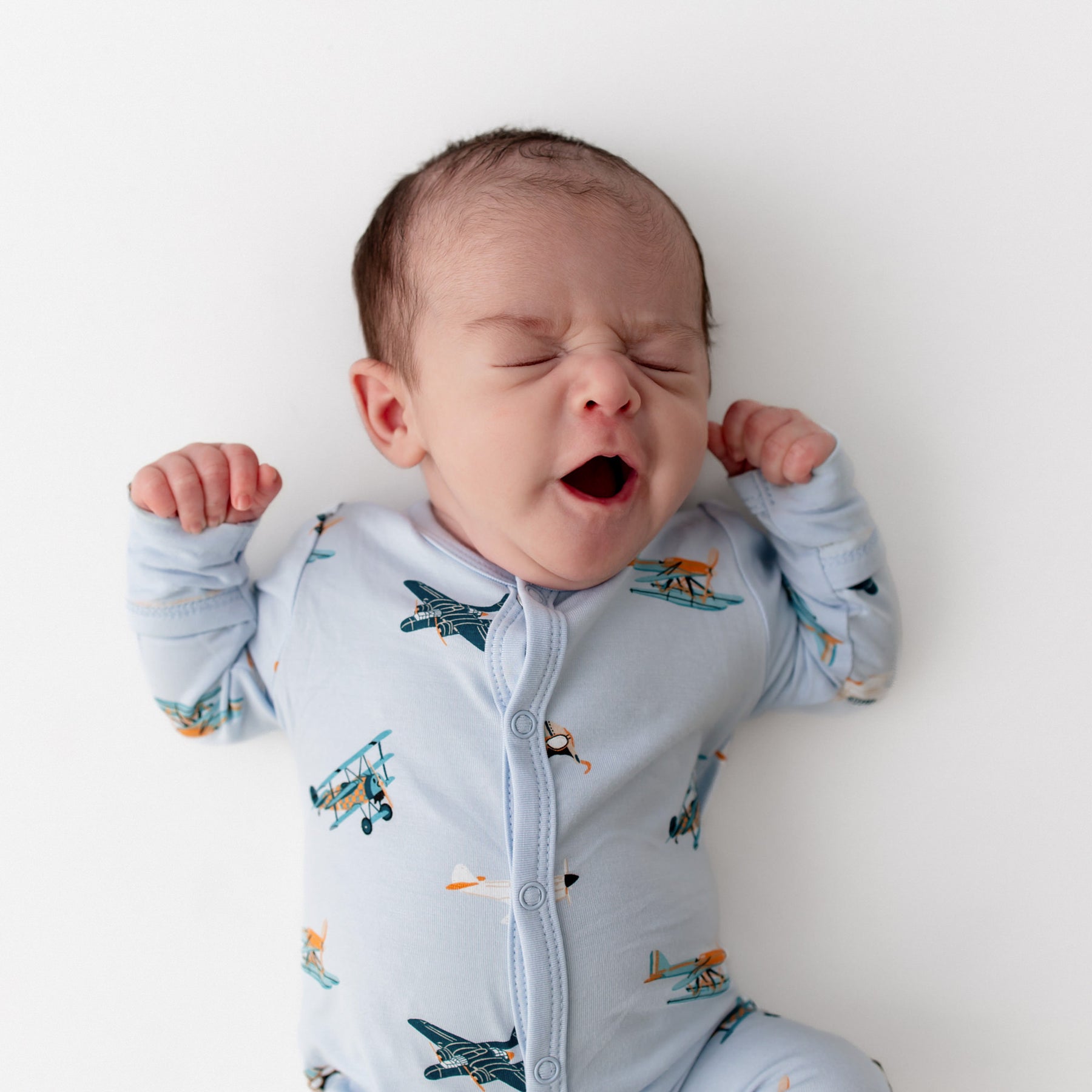 Close up of yawning newborn wearing the Romper in Take Off
