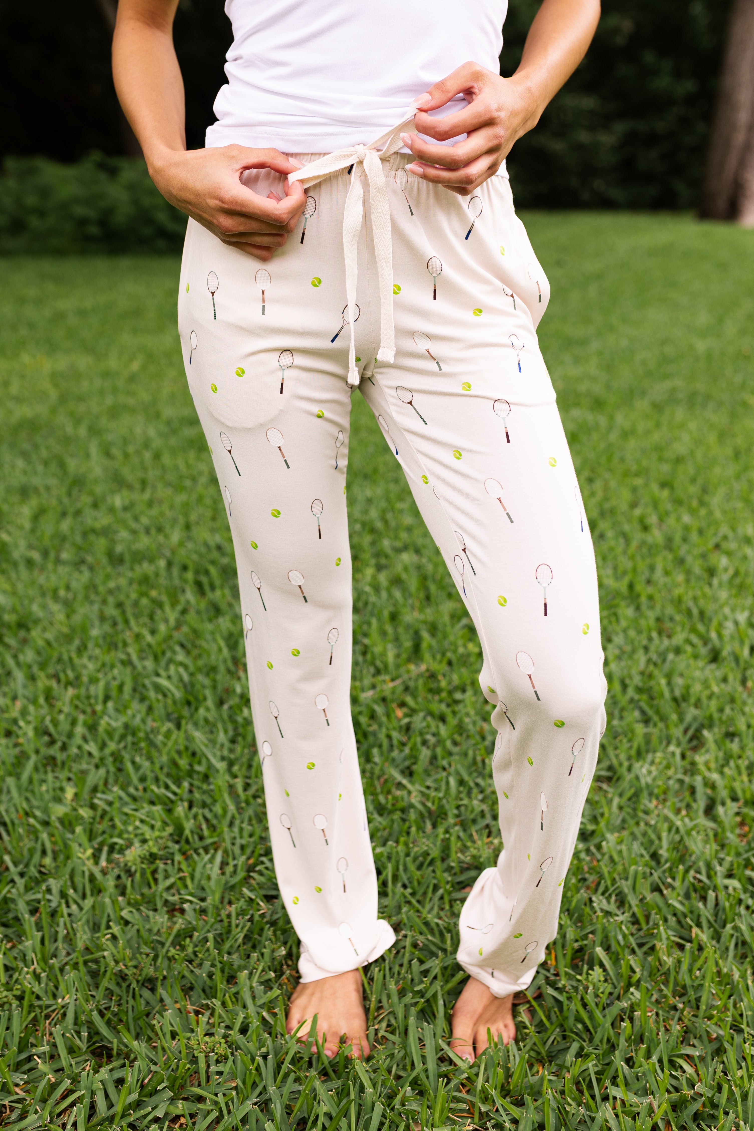 Woman wearing lounge pant with tennis pattern standing on grass