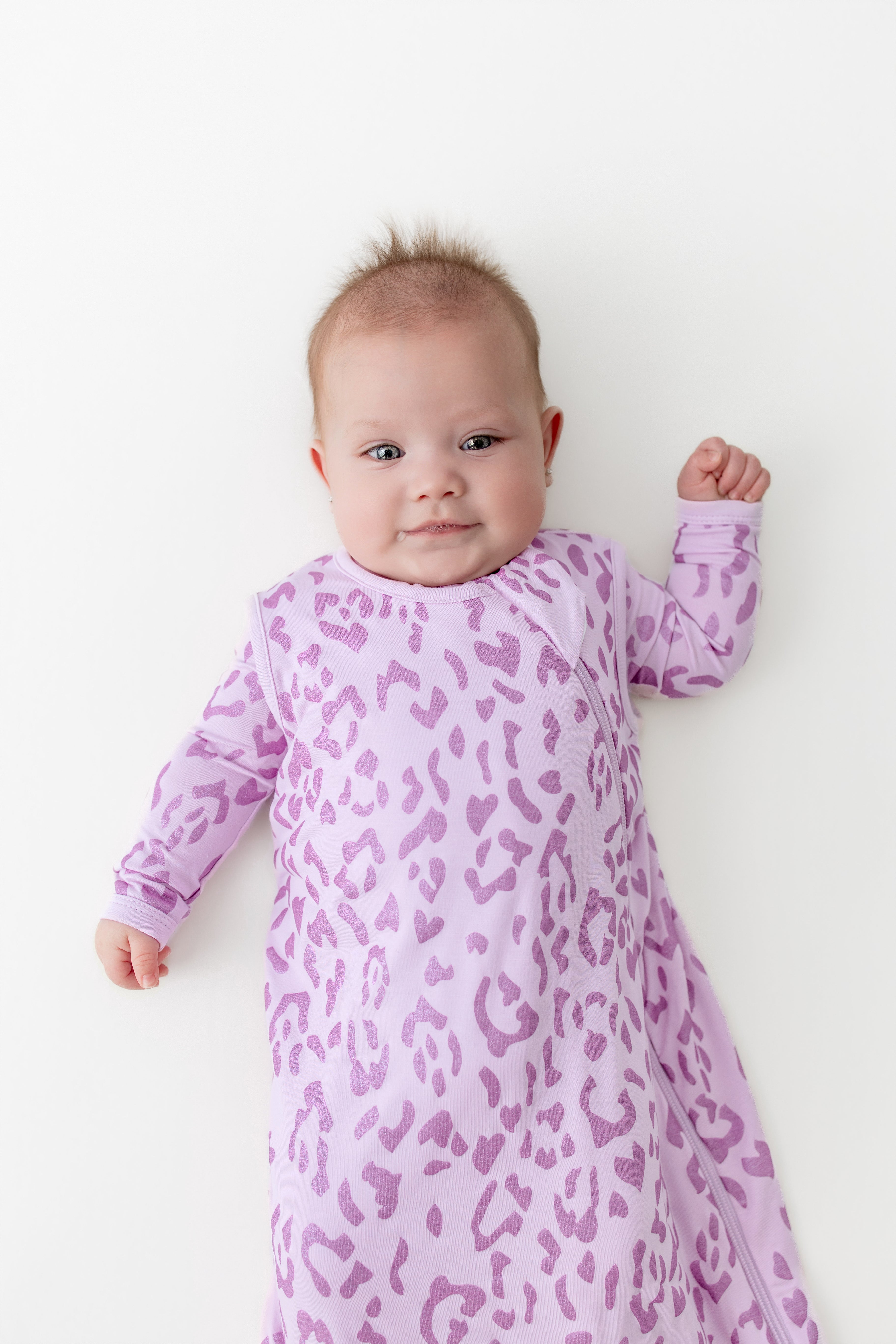 Baby wearing a sleep bag in Thistle Leopard print on a white background