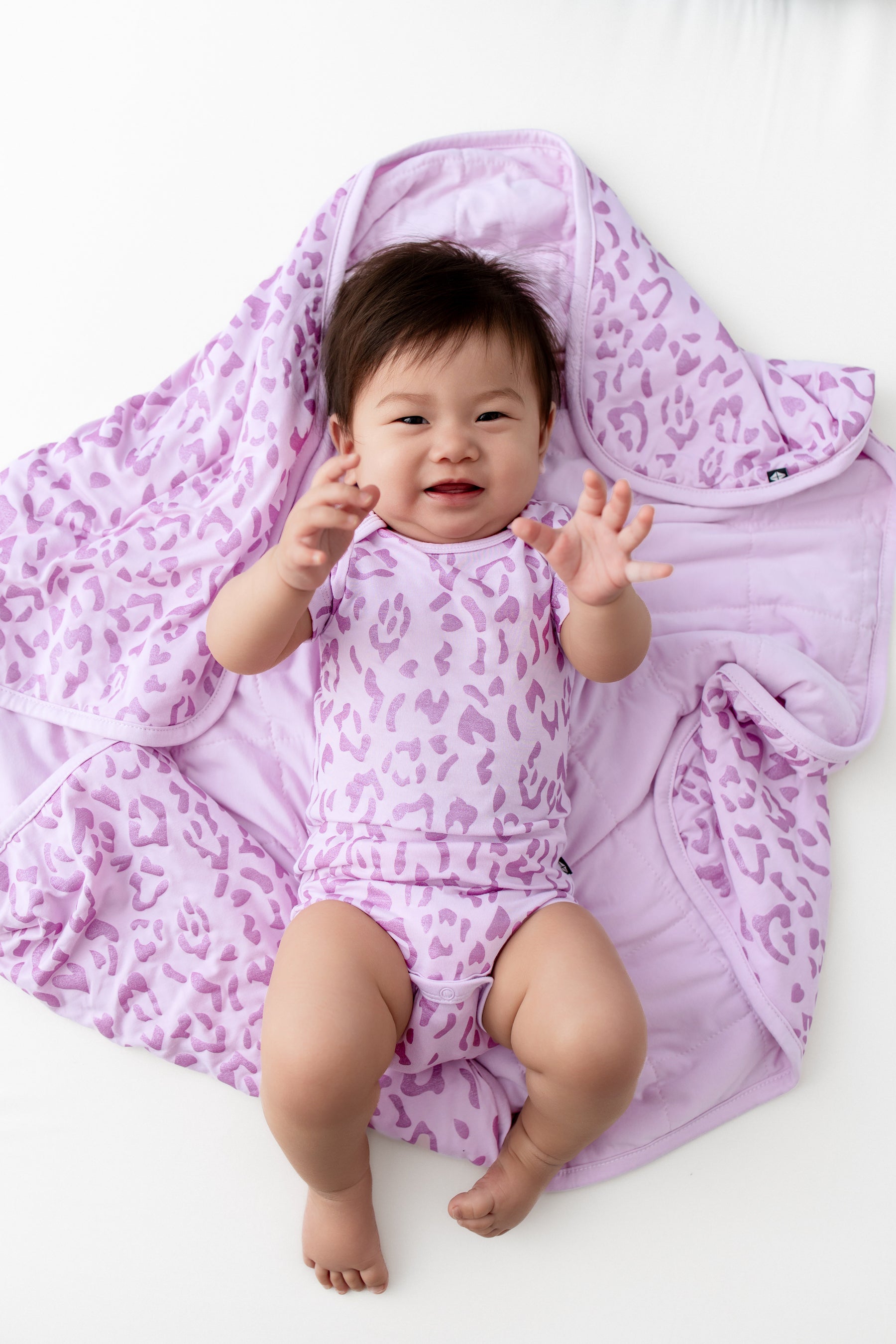 Baby lying over a Baby Blanket with Thistle Leopard print on a white background