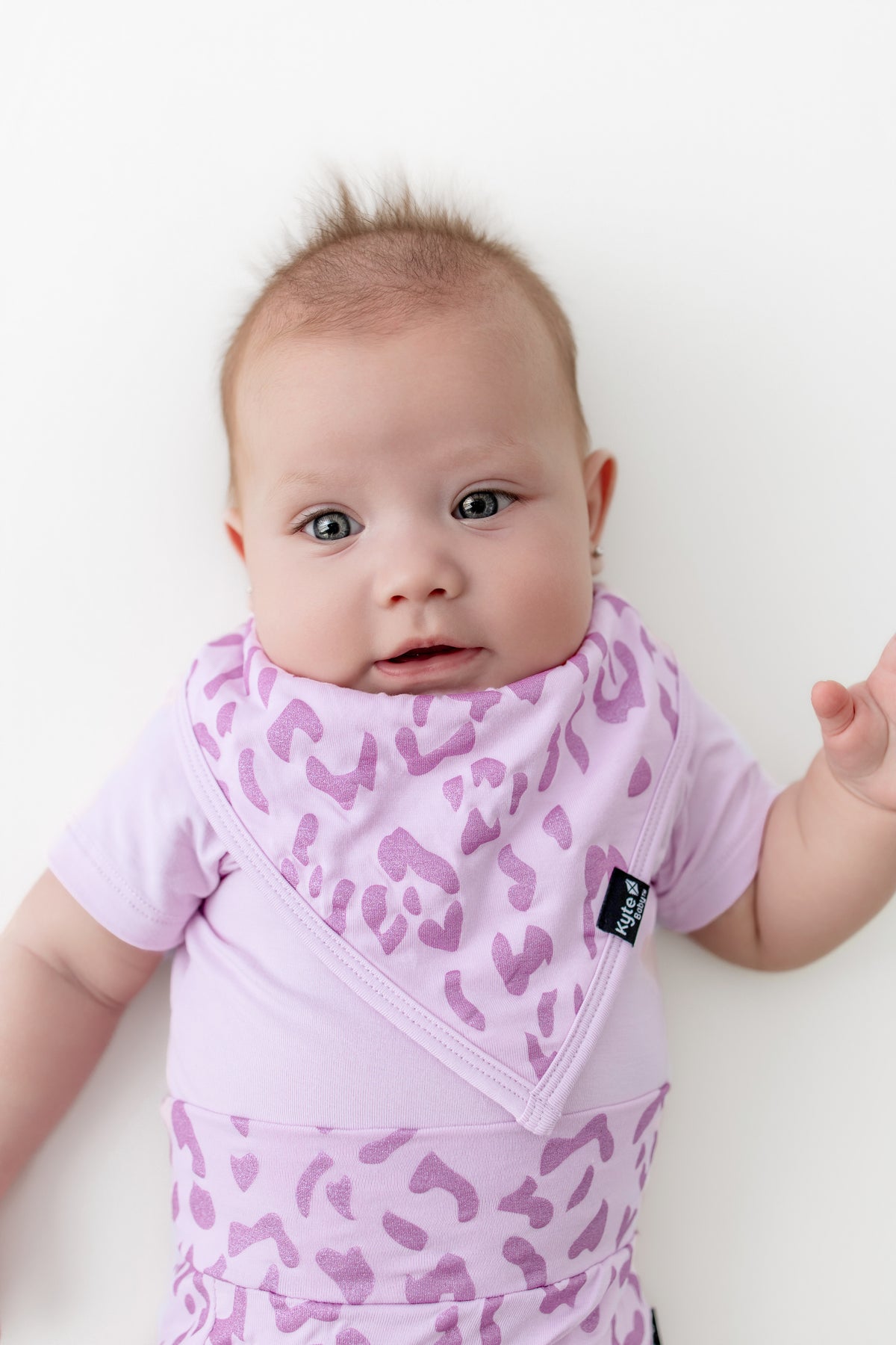 Baby wearing a Thistle Leopard print Bib on a white background