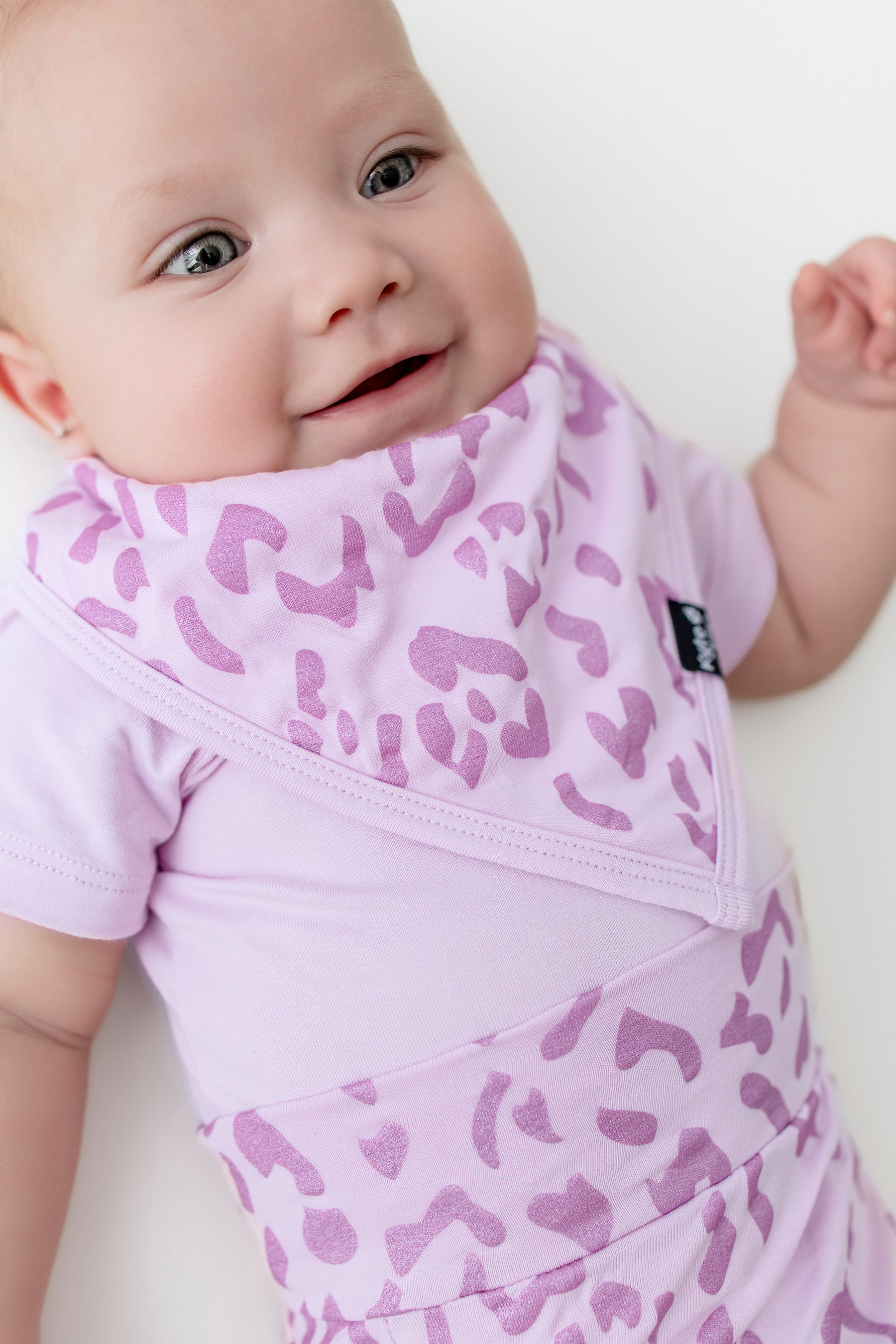 Baby wearing a Thistle Leopard print Bib with a similar print bummies on a white background