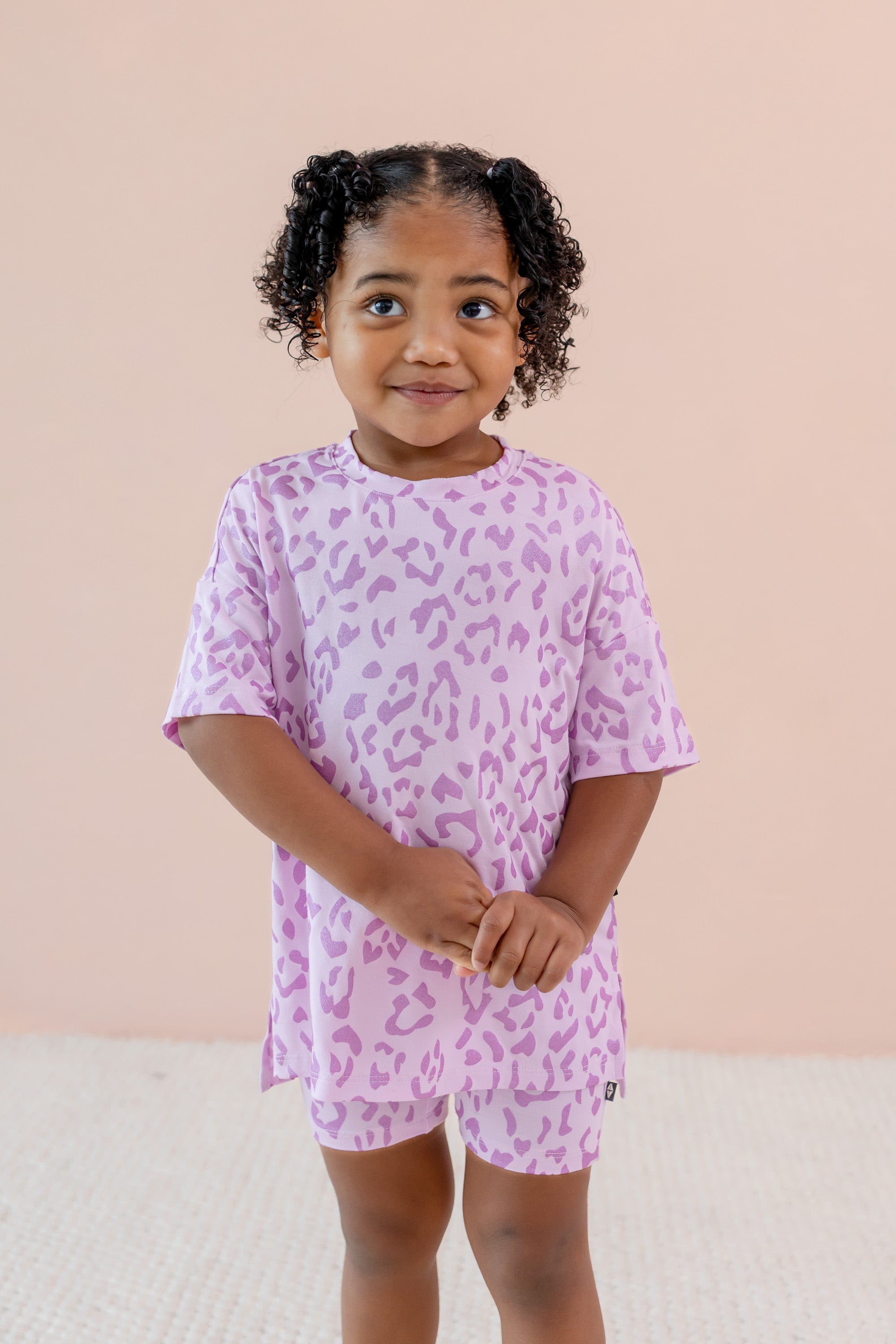 Child wearing Toddler Biker Short set in Thistle Leopard print on a beige background