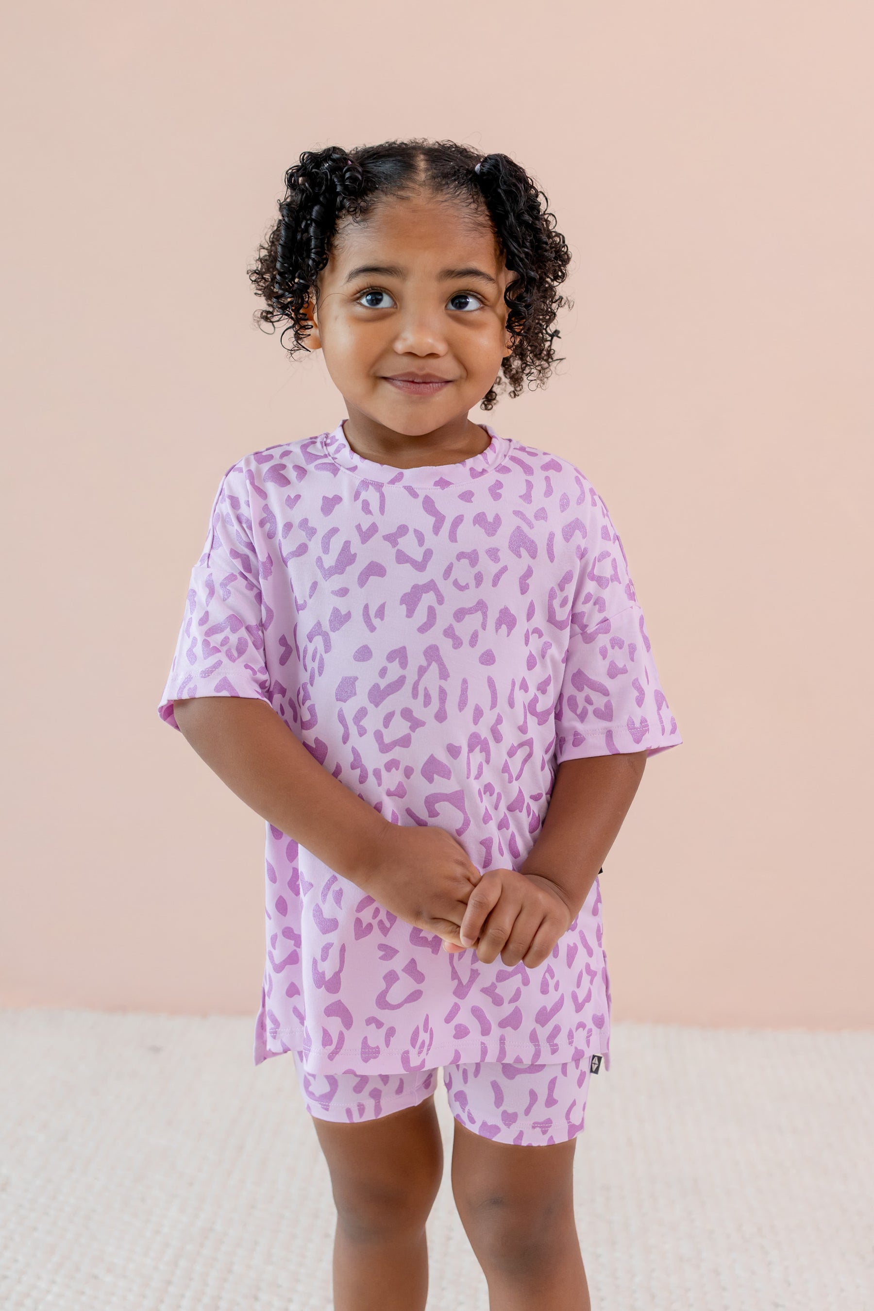 Child wearing Toddler Biker Short set in Thistle Leopard print on a beige background