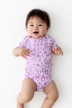 Baby wearing a Thistle Leopard print Bodysuit on a white background