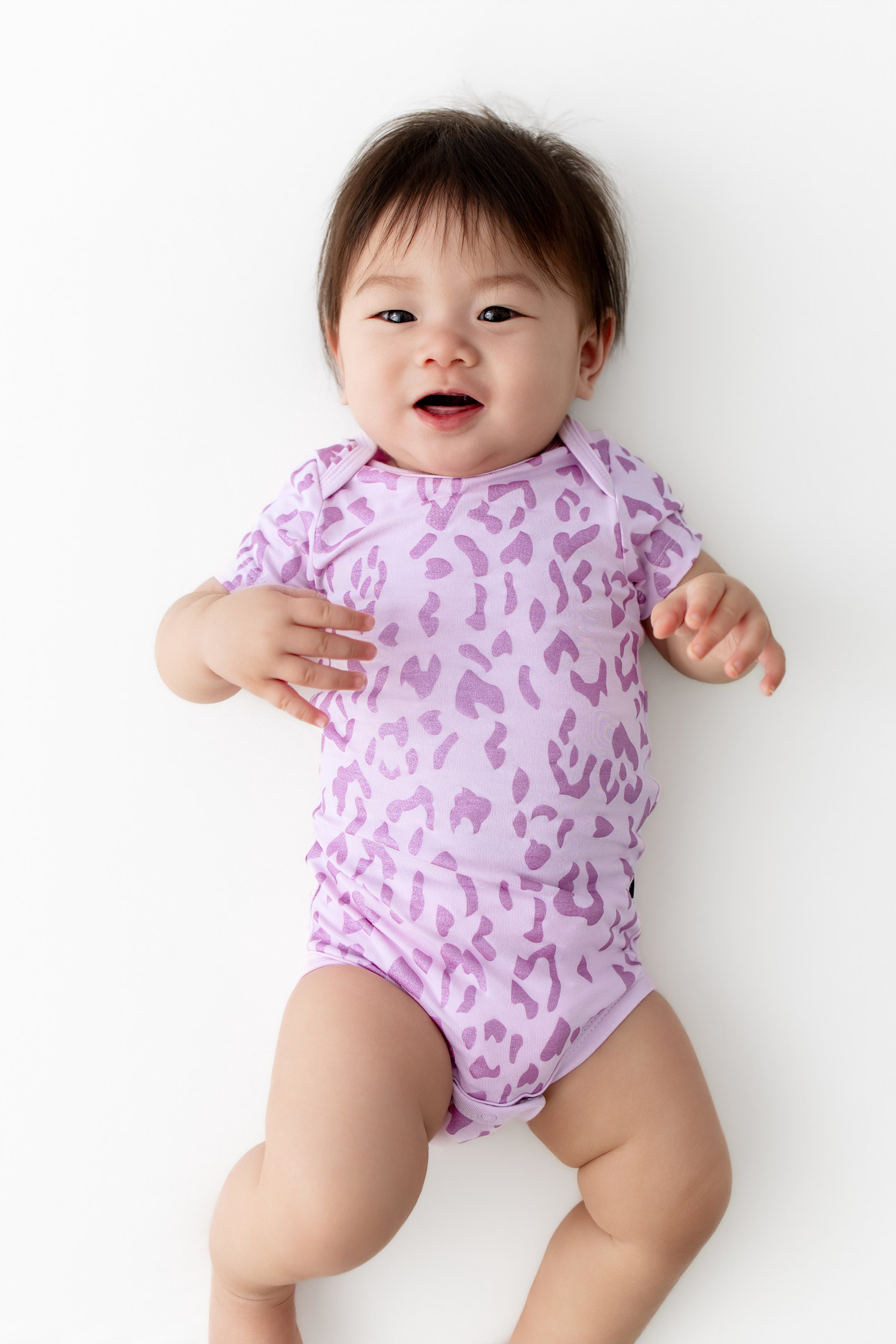 Baby wearing a Thistle Leopard print Bodysuit on a white background
