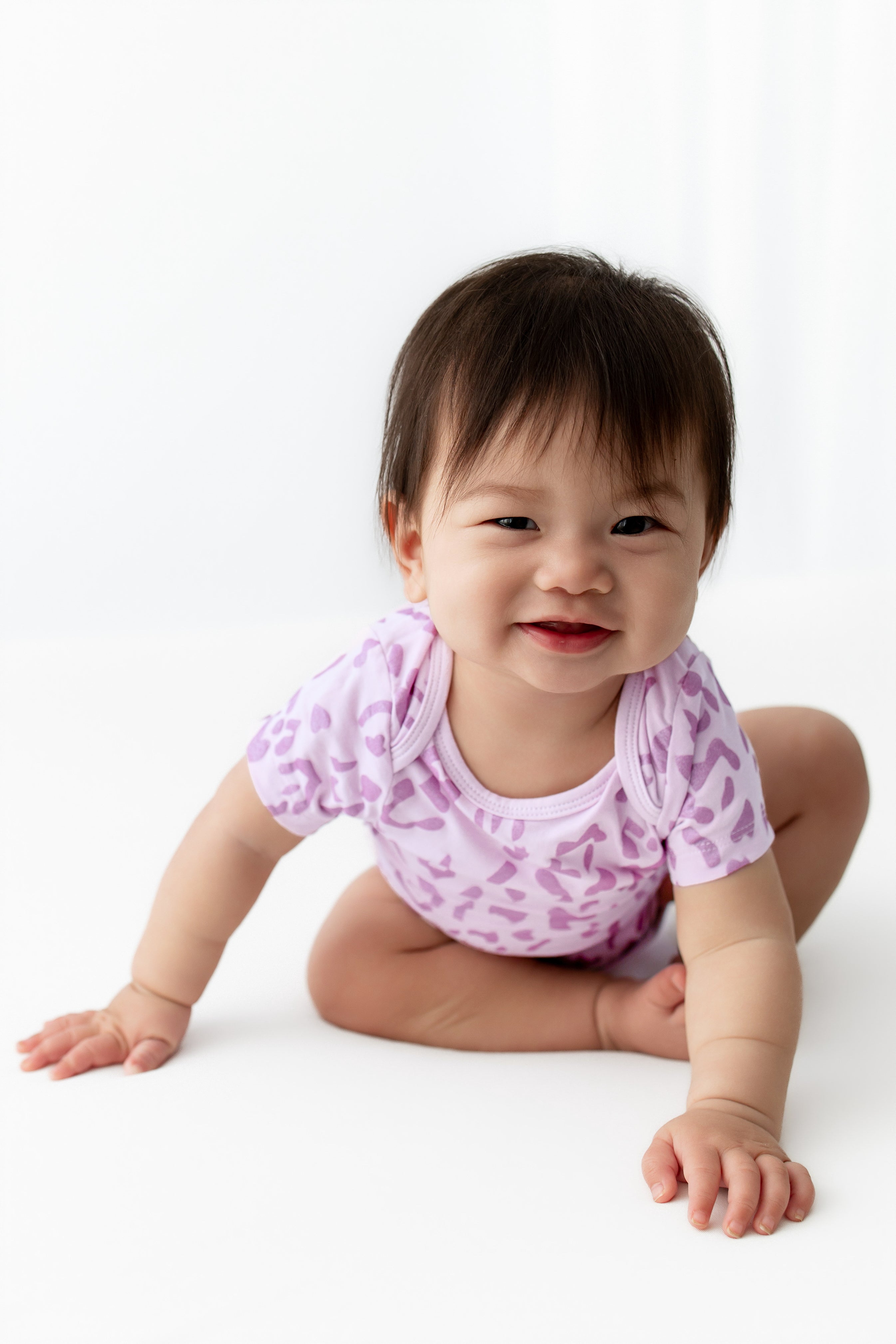 Baby wearing a Thistle Leopard print Bodysuit on a white background