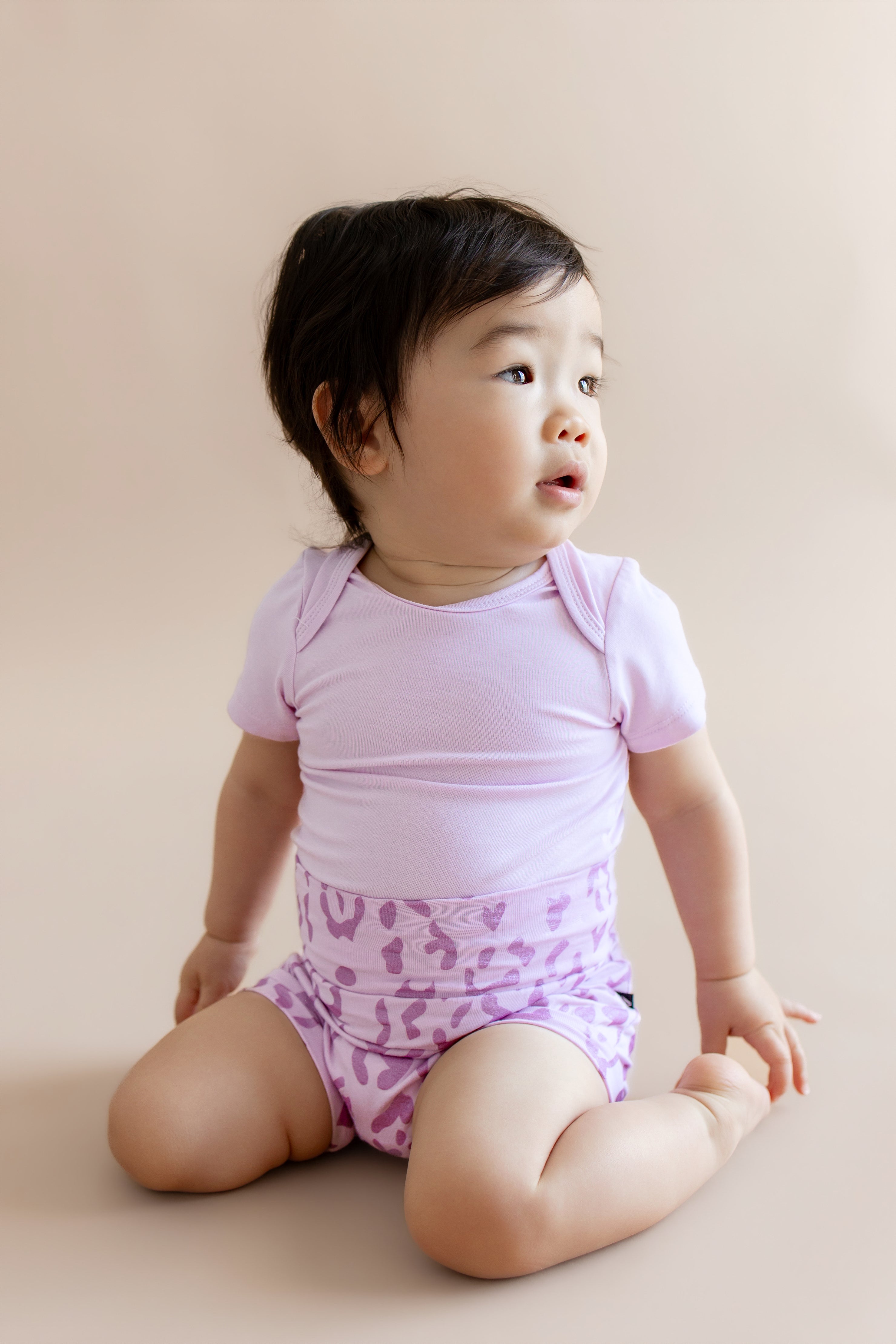 Baby wearing a Thistle Leopard print Bummies over a thistle bodysuit on a beige background