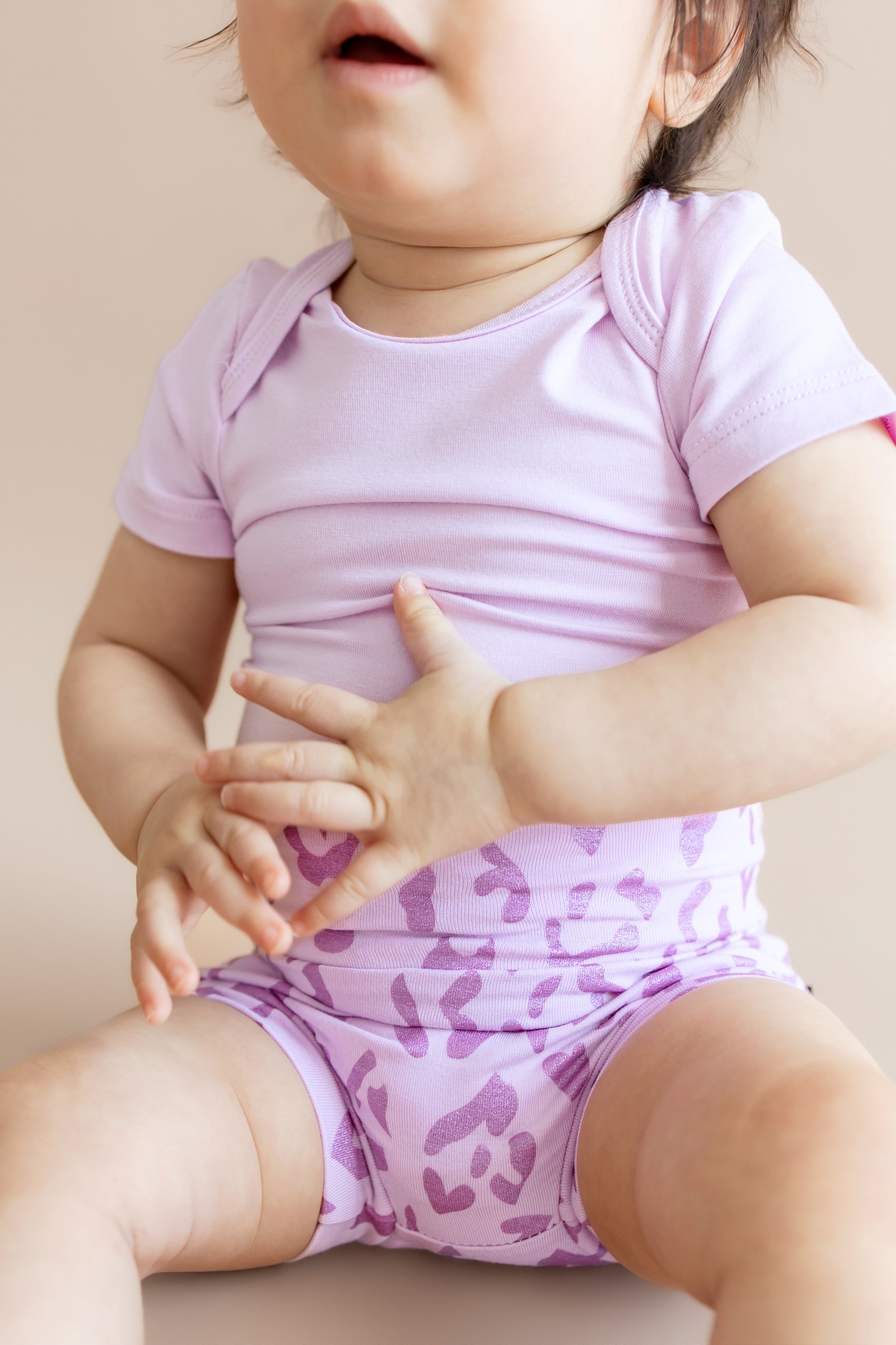 Baby wearing a Thistle Leopard print Bummies over a thistle bodysuit on a beige background