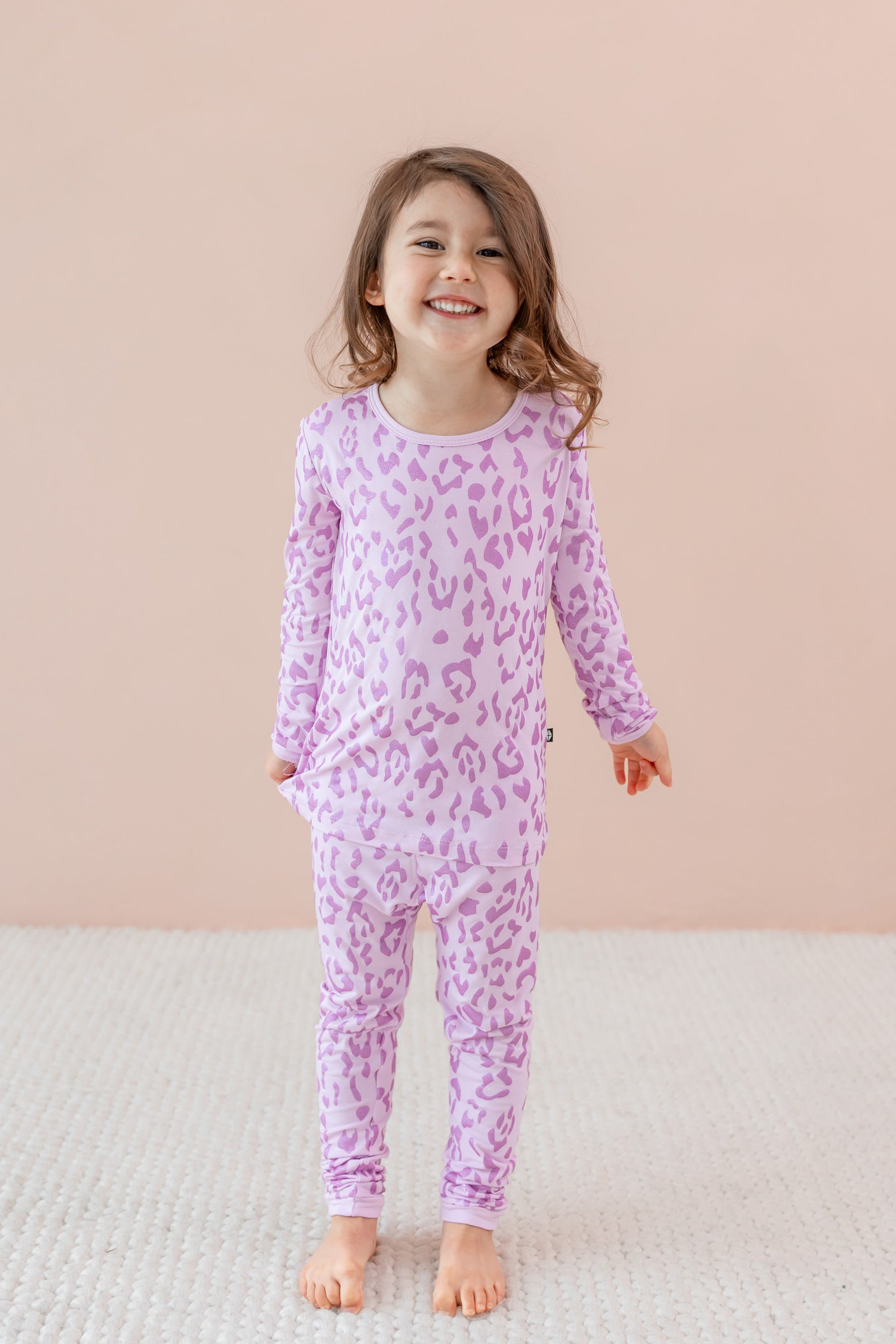 Child wearing Long sleeve pajama set in Thistle Leopard print on a beige background