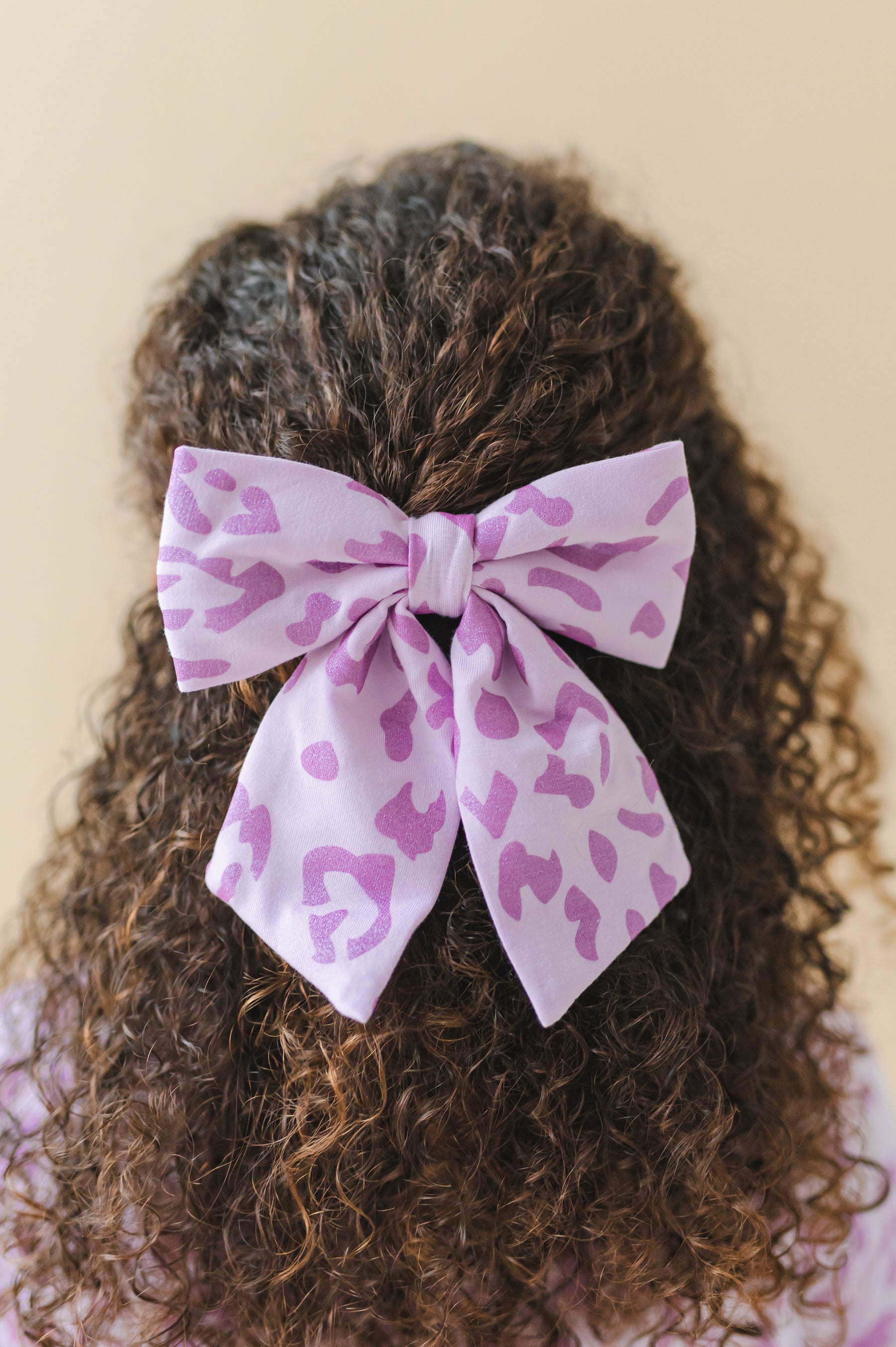 Person wearing a Thistle Leopard print Large alligator clip bow on a beige background