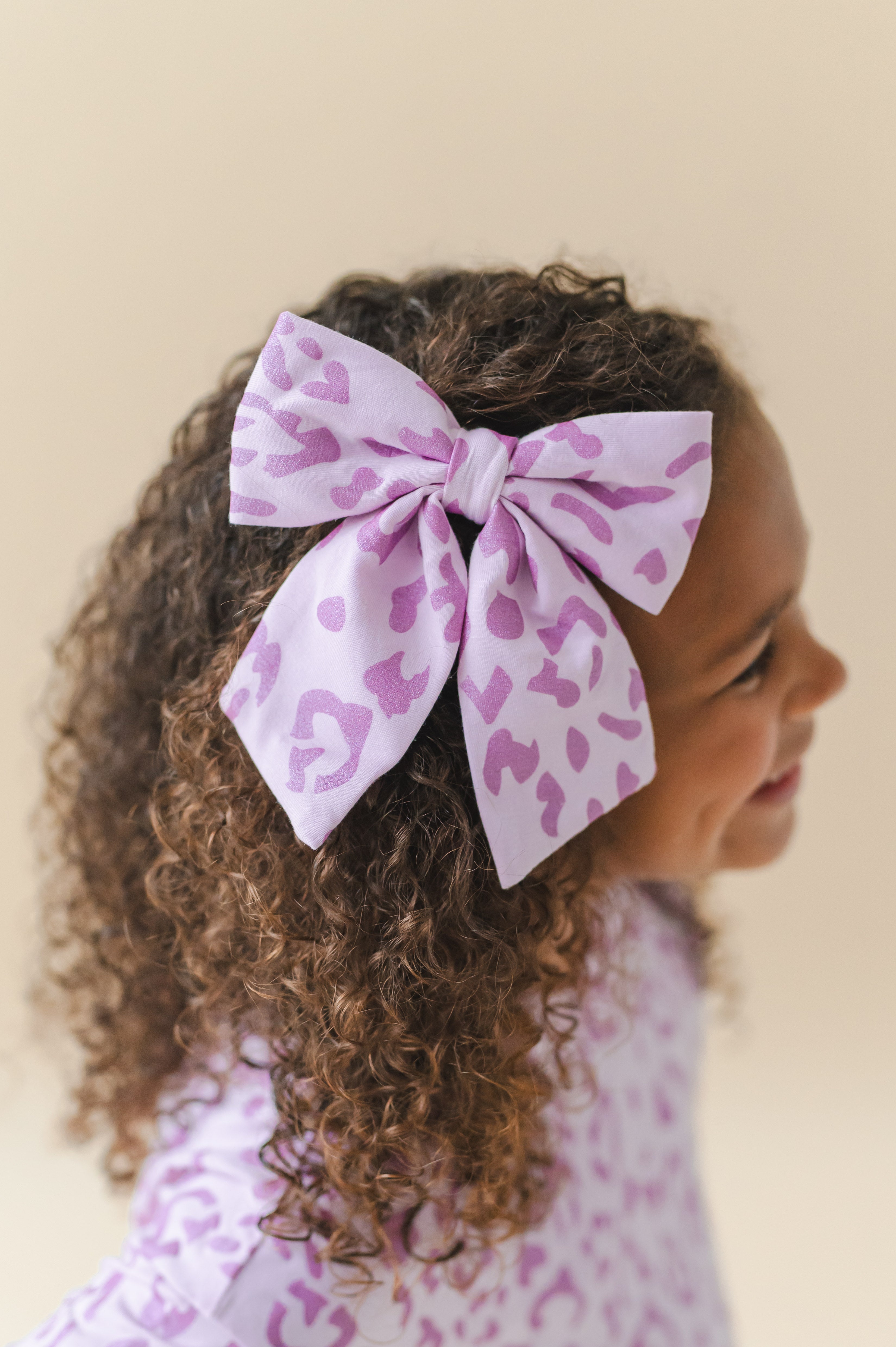 Child wearing a Thistle Leopard print Large alligator clip bow on a beige background