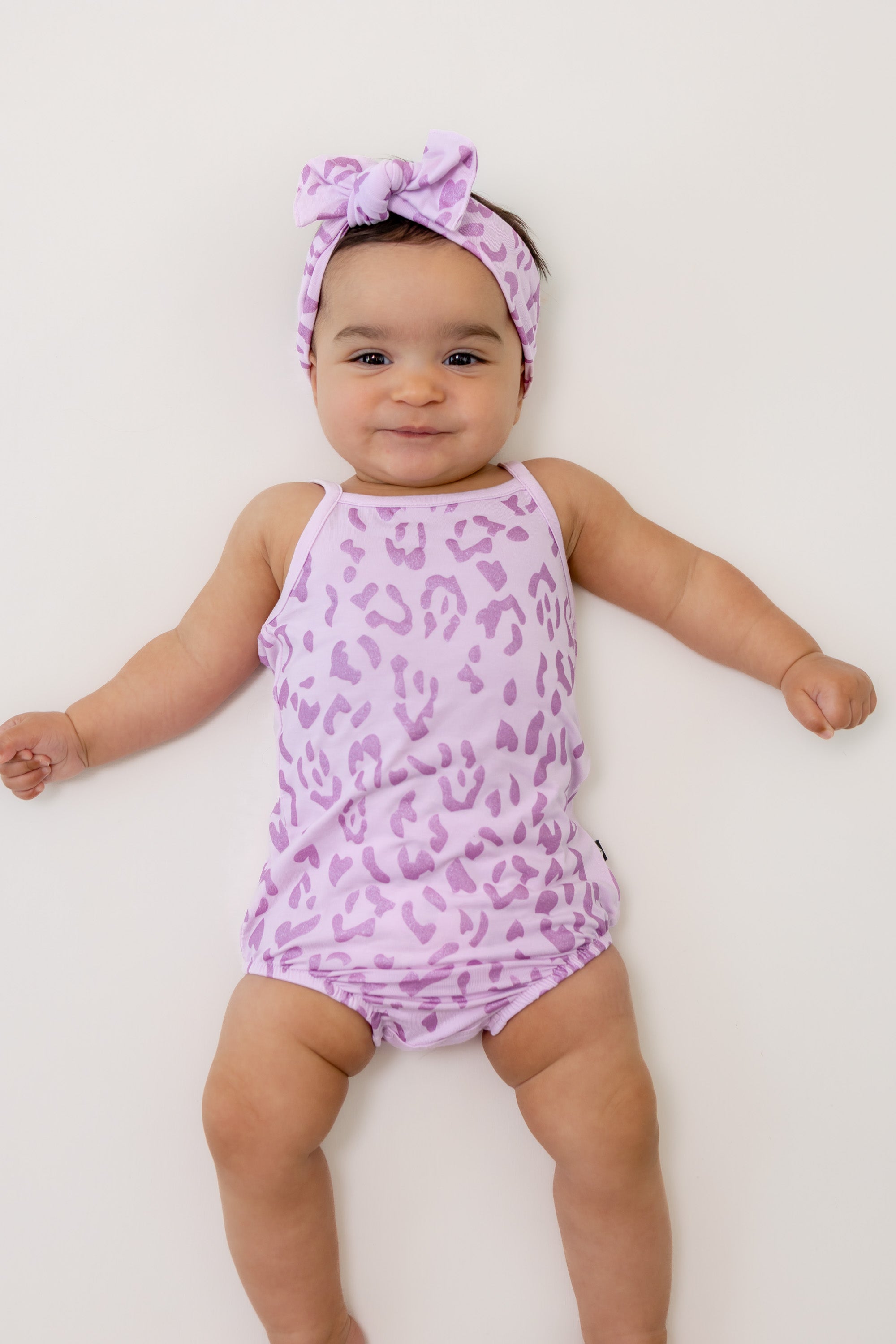 Baby wearing Thistle Leopard print Spaghetti Strap Leotard and bow headband on a white background