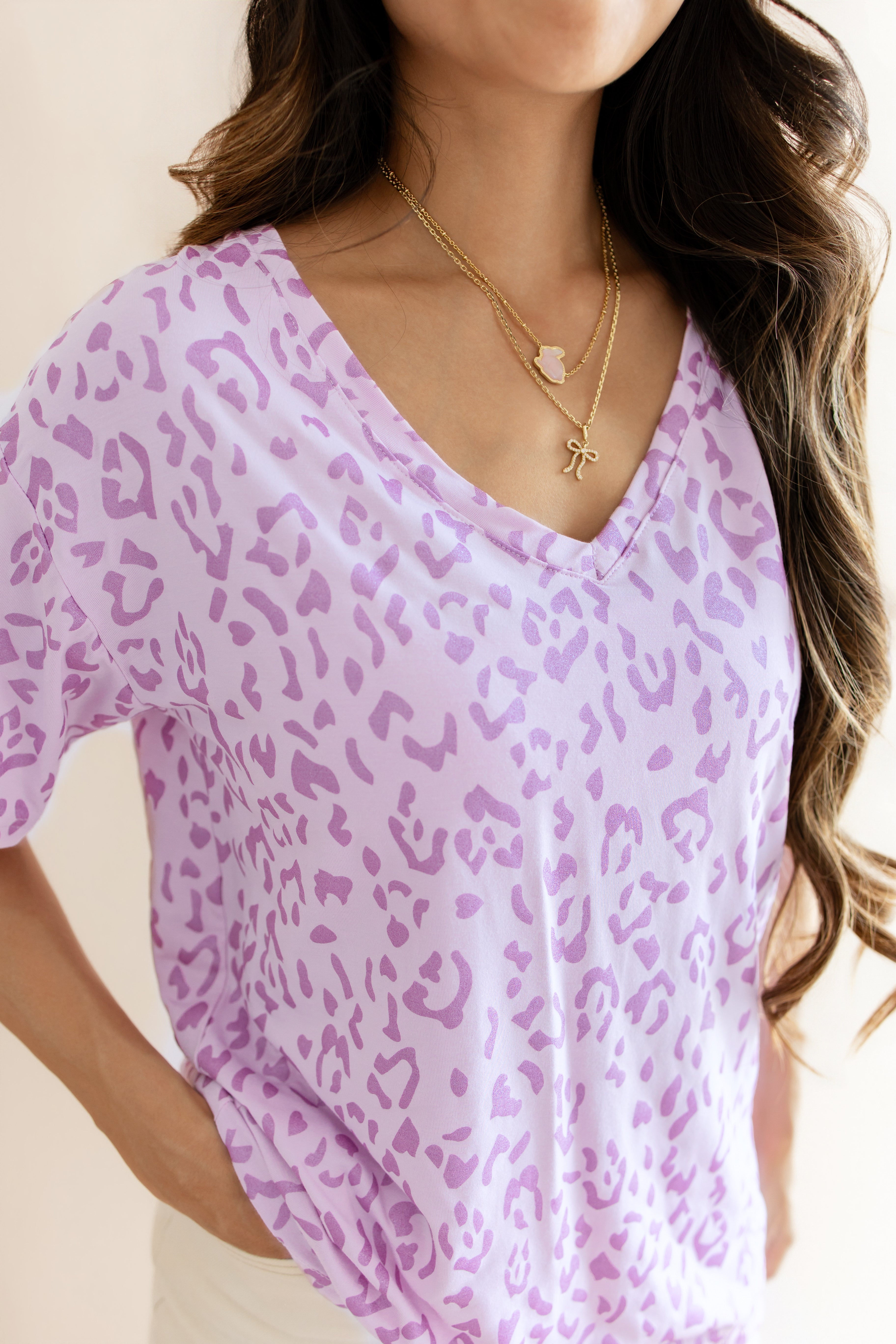 Women's Relaxed Fit V-Neck in Thistle Leopard print over a white pant on a beige background