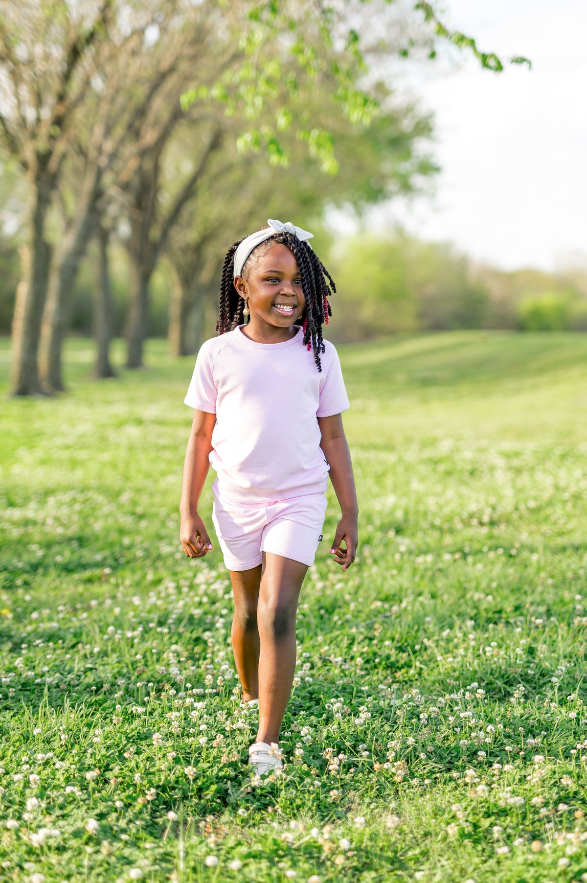 Young girl walking through a green field wearing the Short Sleeve Jogger Set in Thistle
