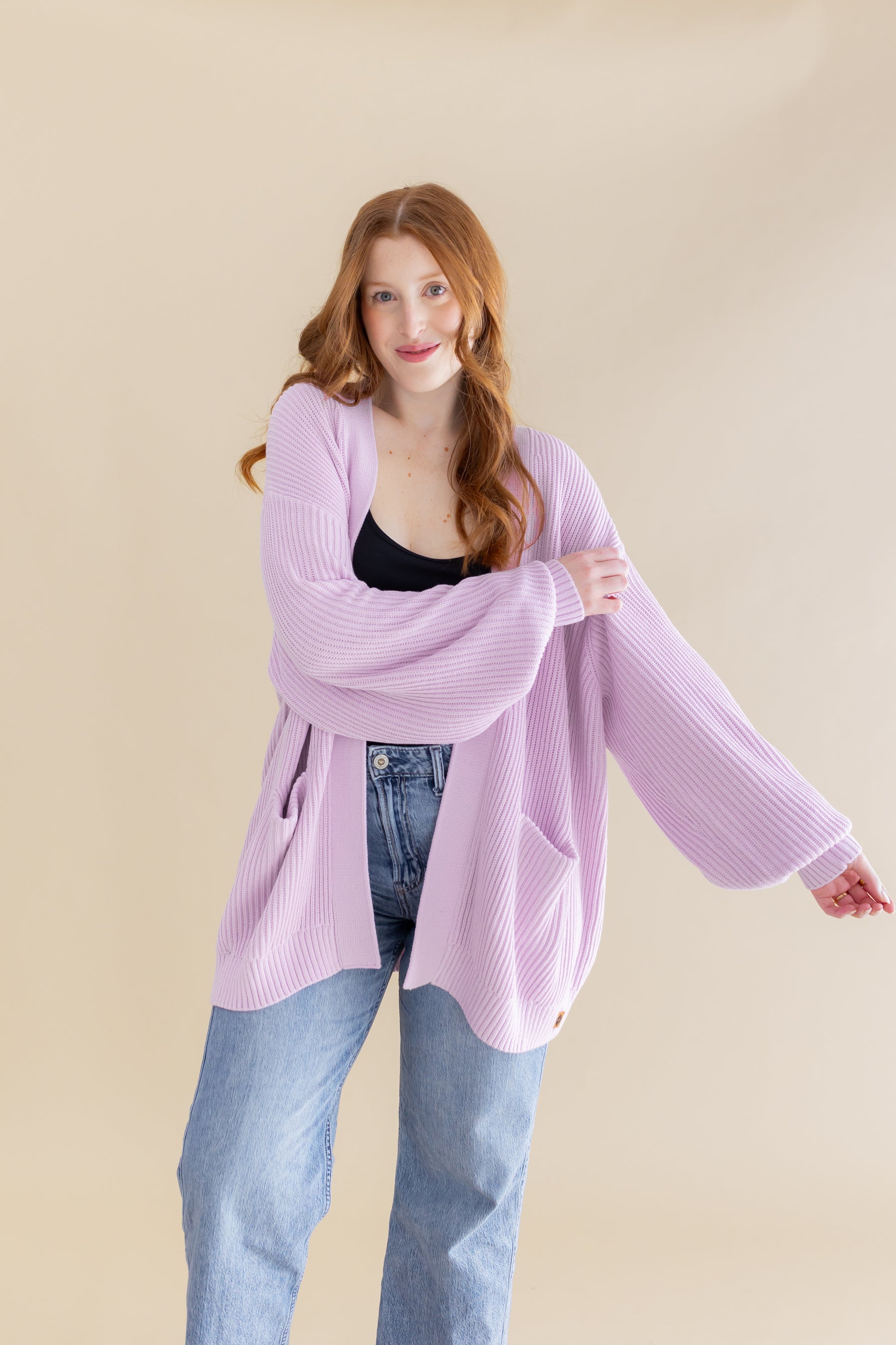 Female model posing with one arm out showing the relaxed fit in the arms of the Chunky Knit Women's Oversized Cardigan in Thistle