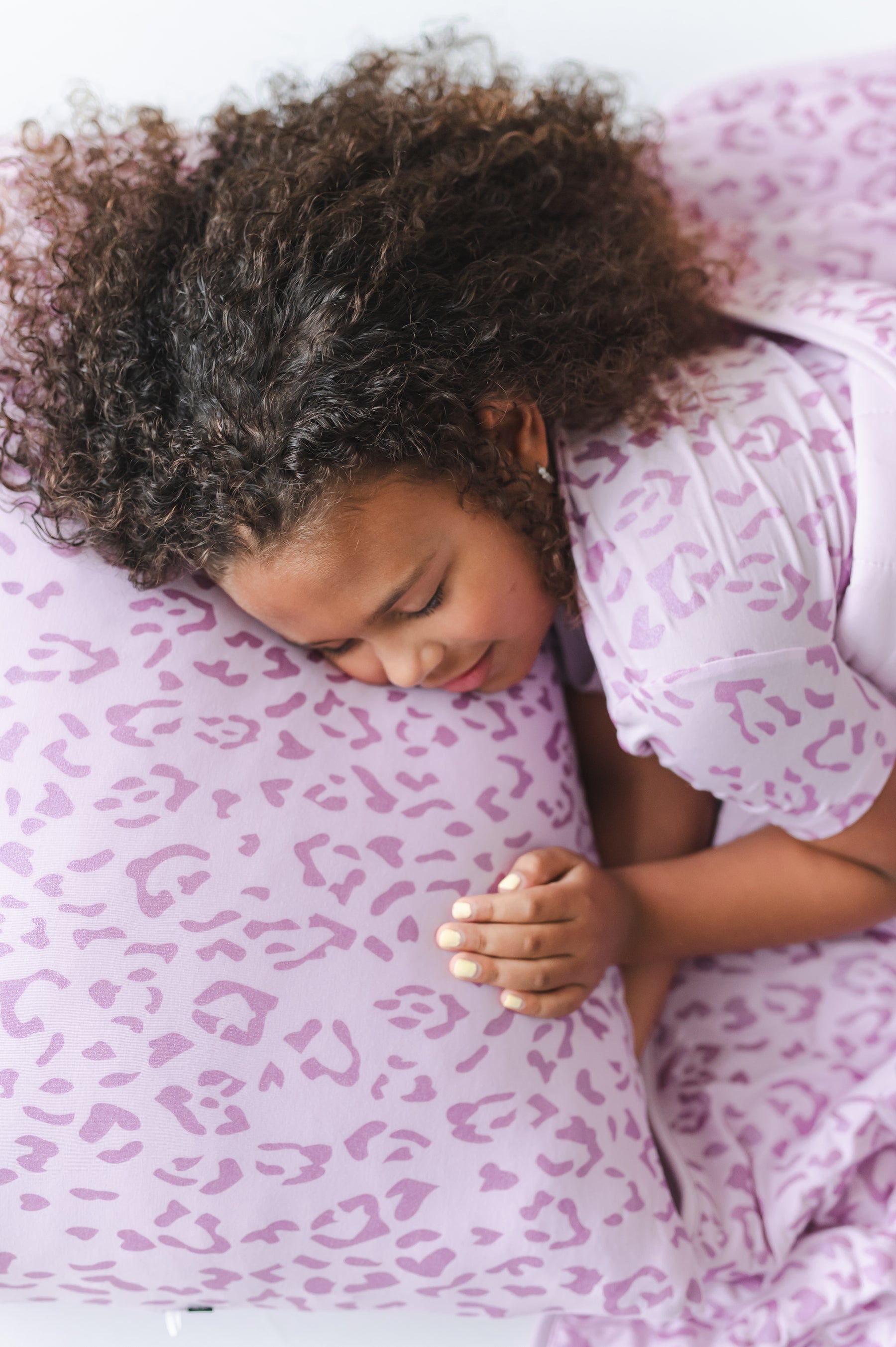 Child sleeping on a Thistle Leopard print Standard pillowcase wearing a similar print shirt under a Thistle leopard blanket