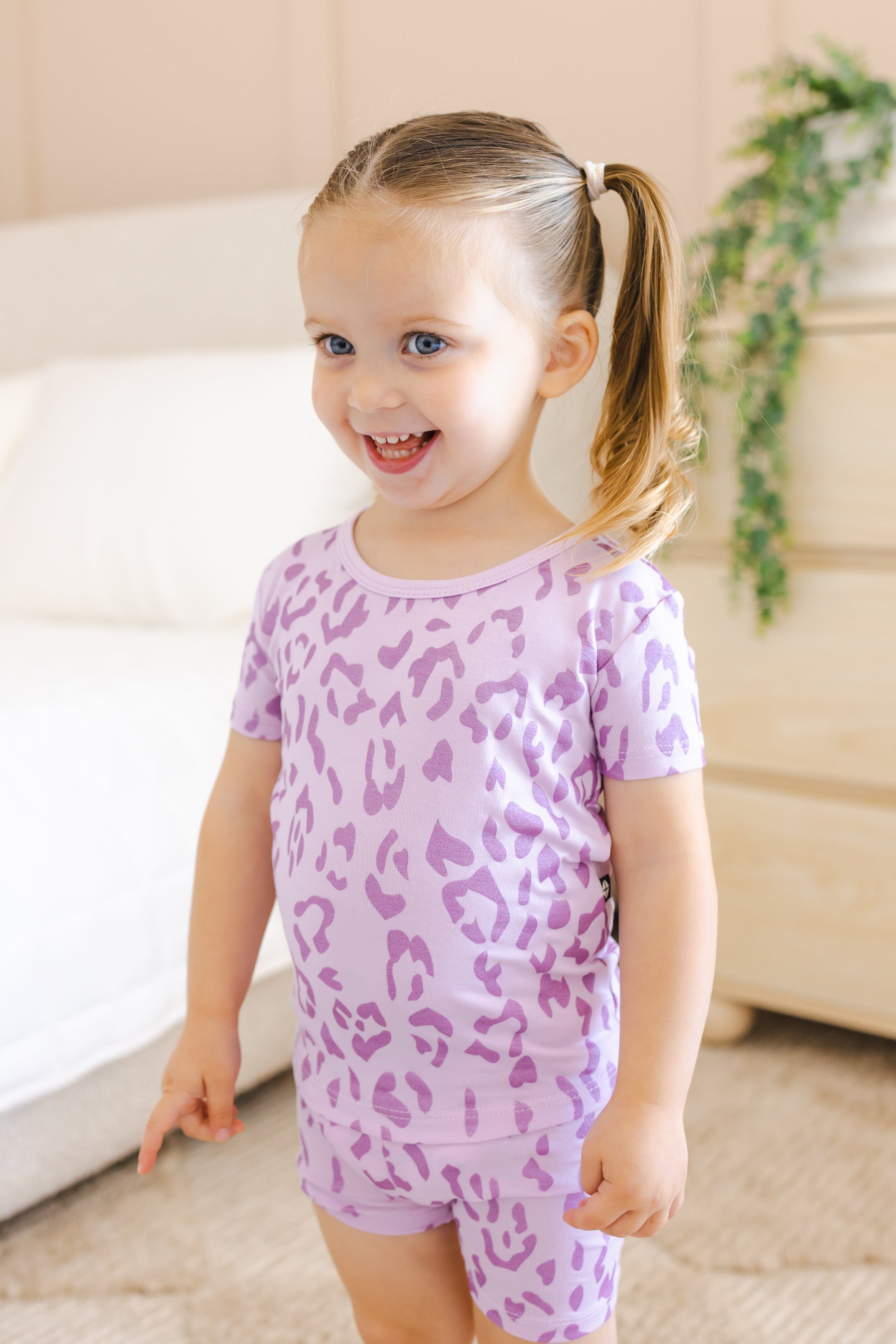 Child smiling in Short Sleeve Pajamas in Thistle Leopard print in a room